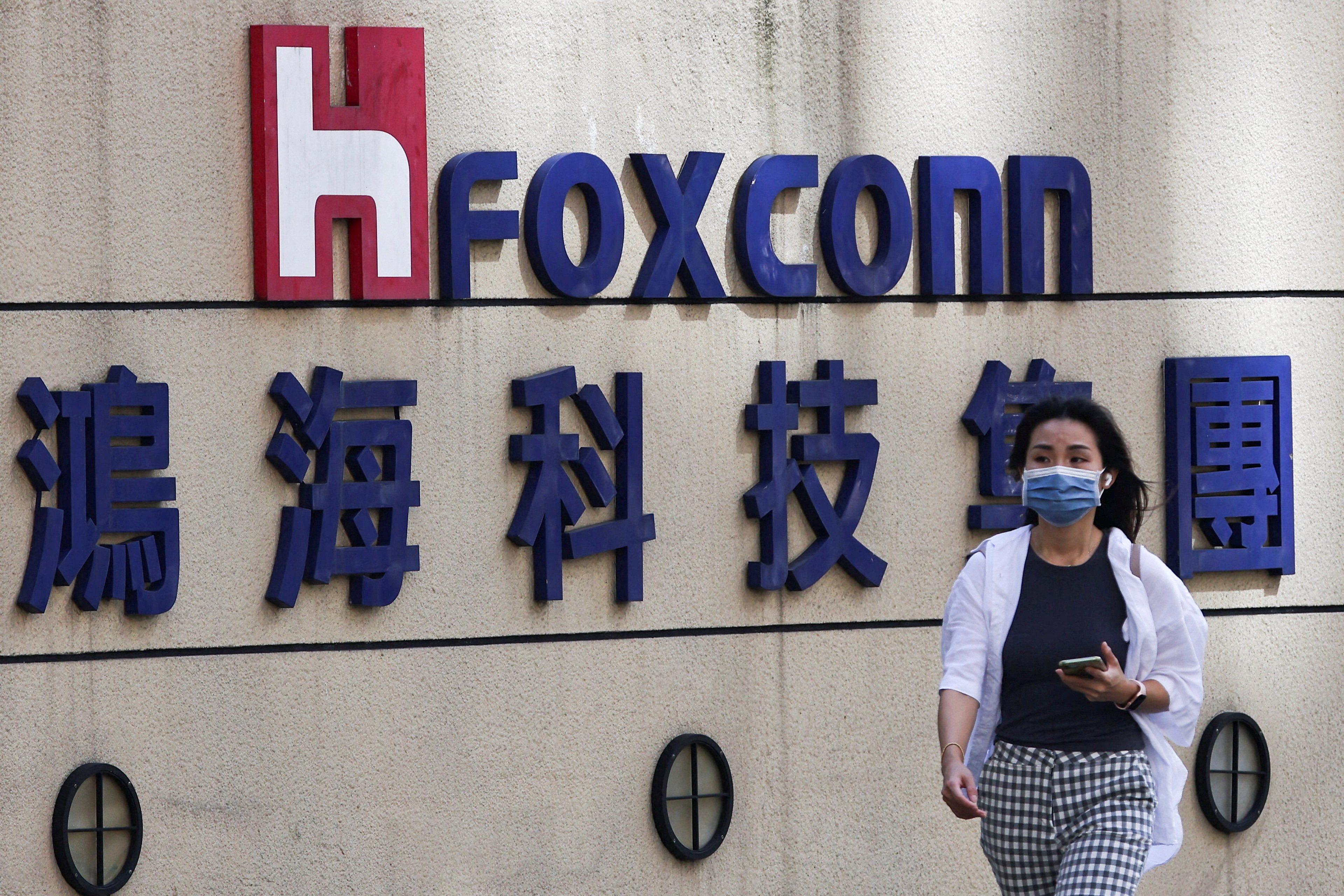 A woman walks past the logo of Foxconn Technology Group outside the company’s headquarters in Taipei on November 9, 2022. Photo: Reuters 