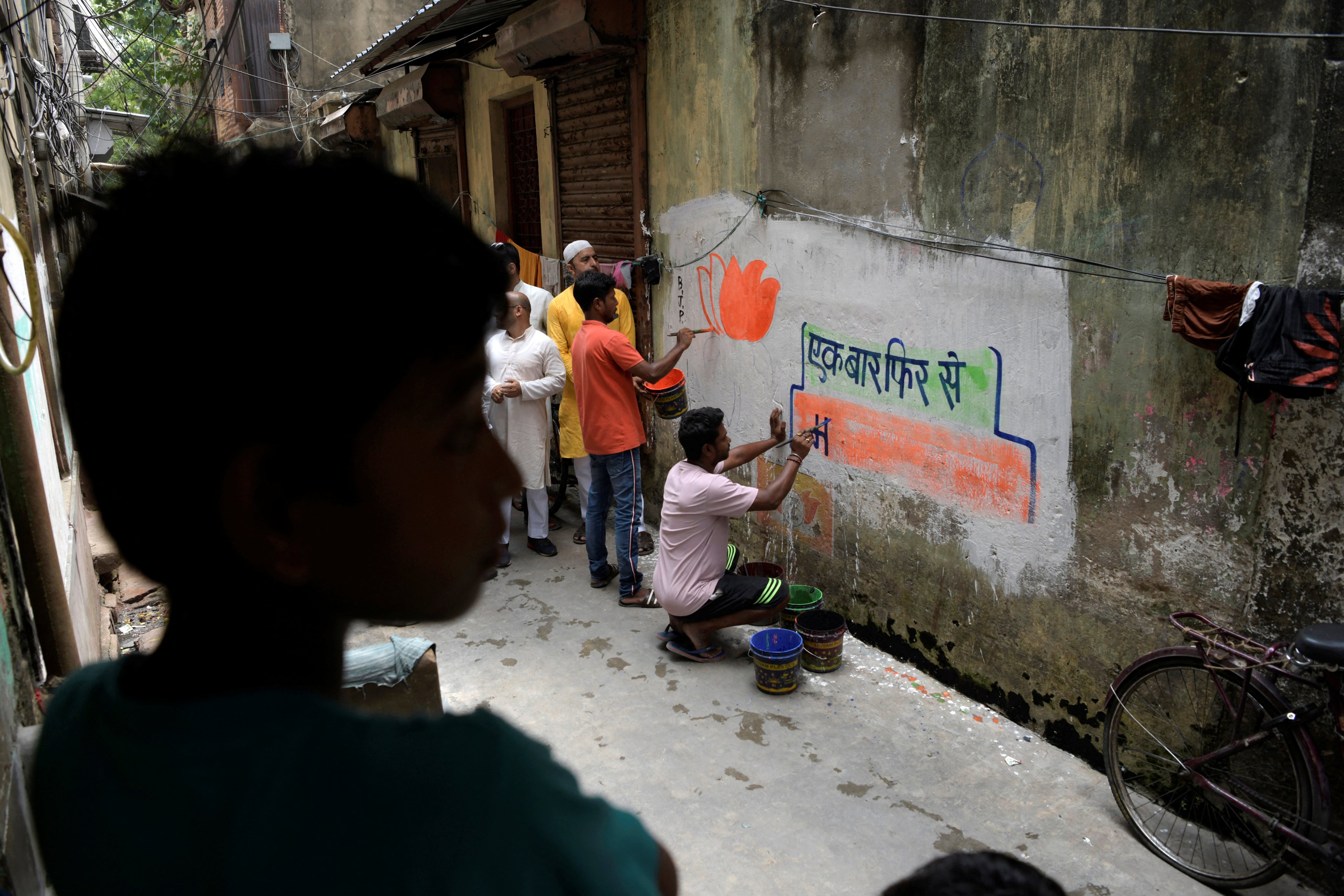 Workers from India’s ruling Bharatiya Janata Party (BJP) paint slogans and party symbols on a wall in Kolkata as part of an outreach programme. Photo: Reuters