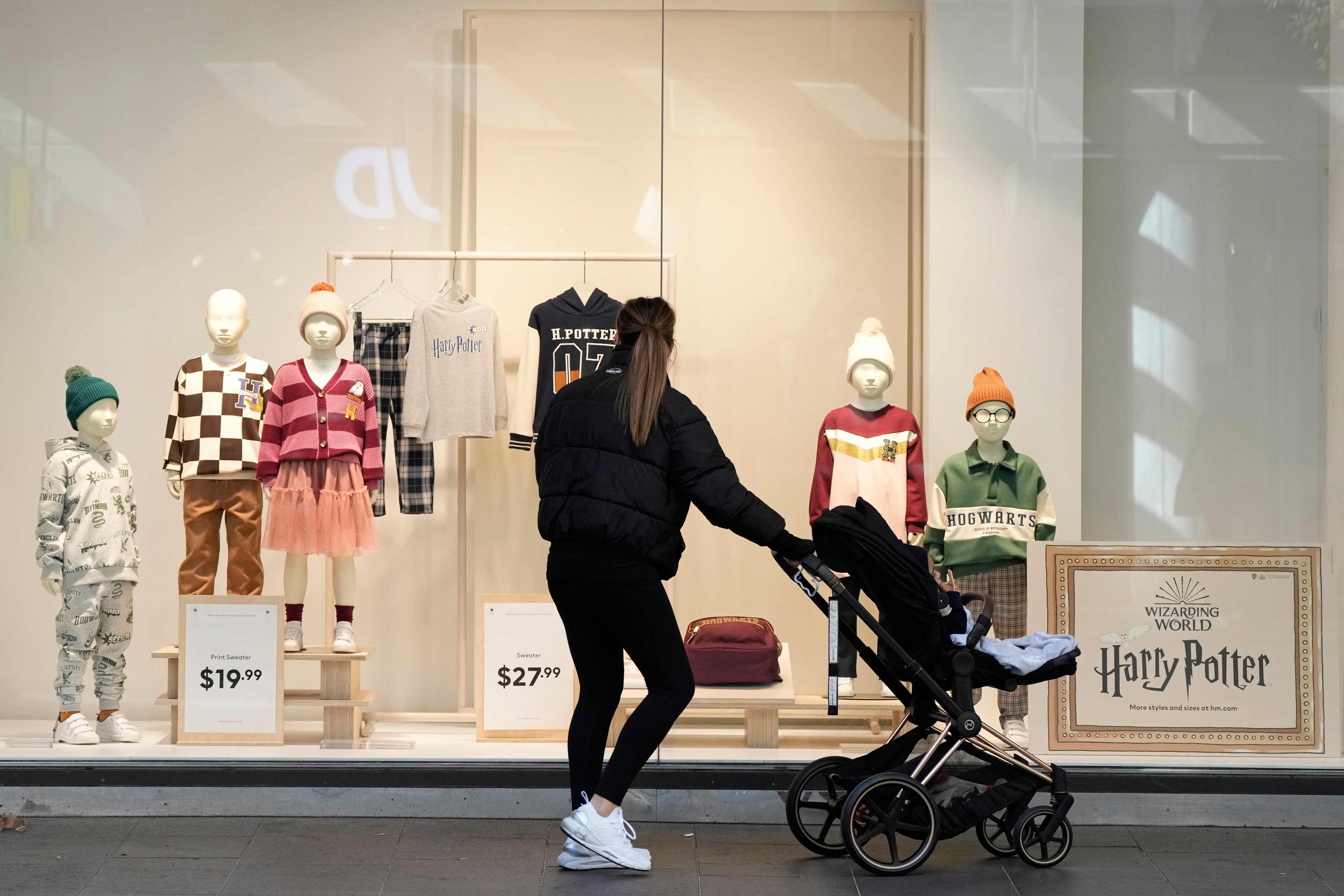 A woman pushing her child in a pram stops to look in a shop window in Sydney. Women in Australia who have at least one child earn A$2 million (US$1.26 million) less over their lifetime than men, a new report found. Photo: AP