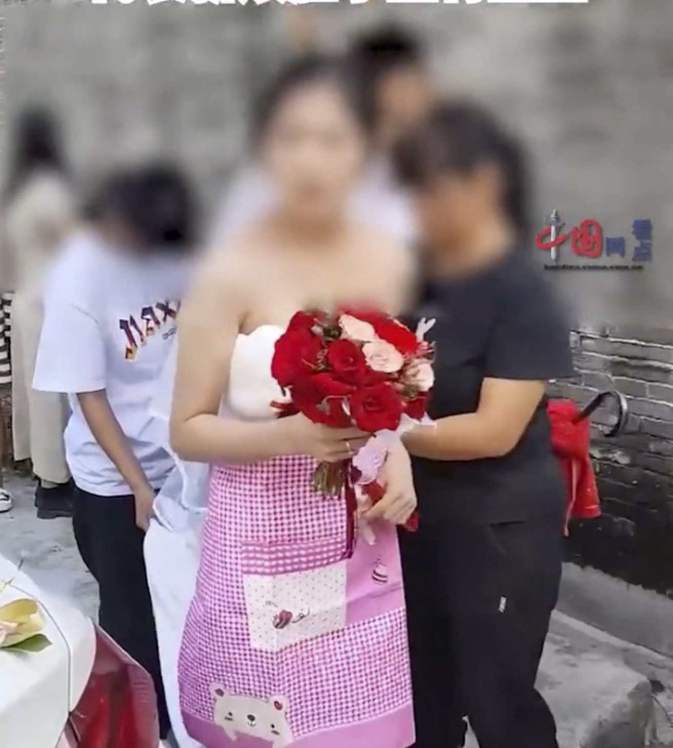 Two older women at the wedding are seen putting the apron on the bride at the ceremony. Photo: Weibo