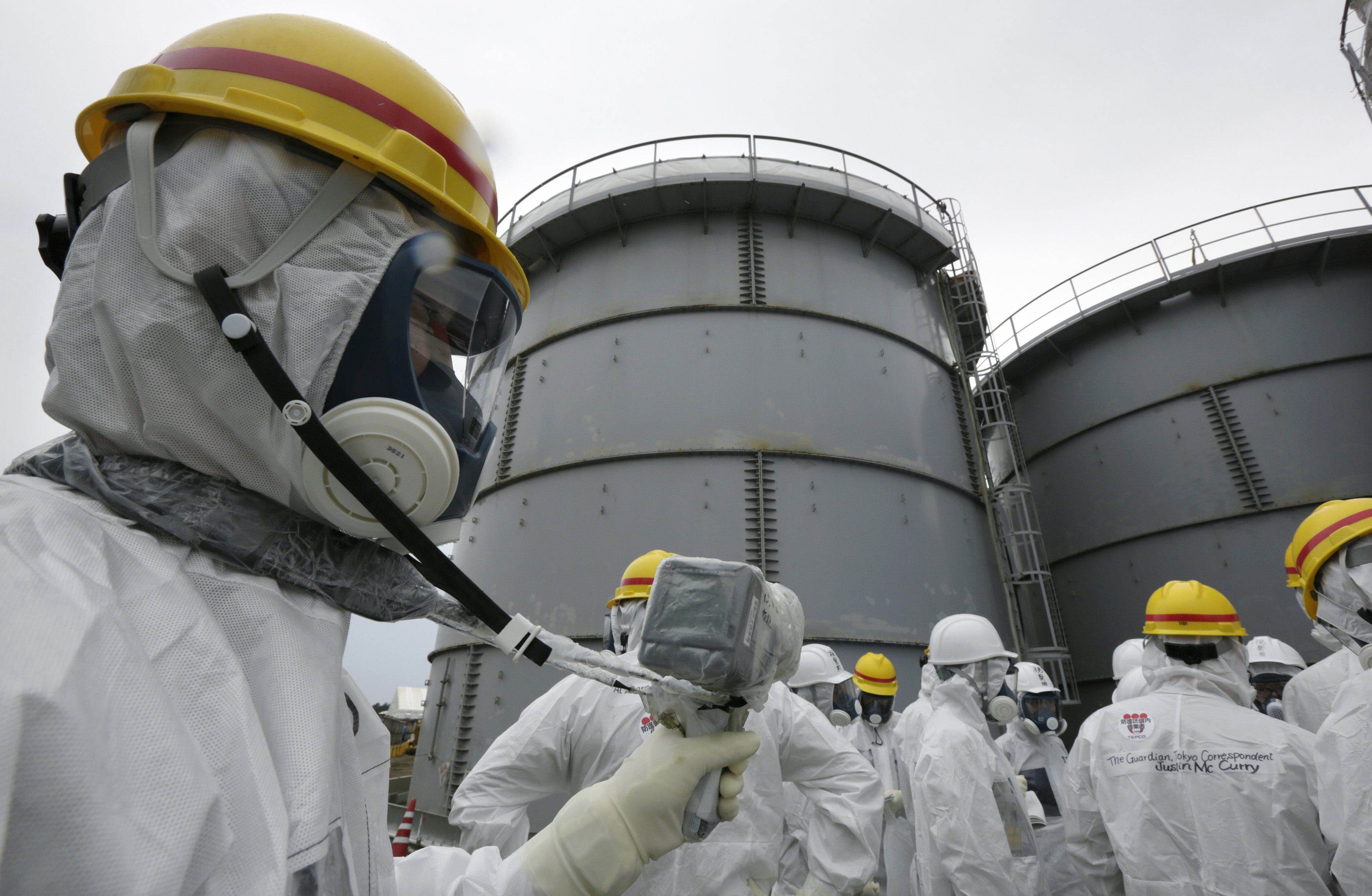 A Tokyo Electric Power Co employee wearing a protective suit and mask uses a survey meter near storage tanks for radioactive water. Photo: Reuters/File