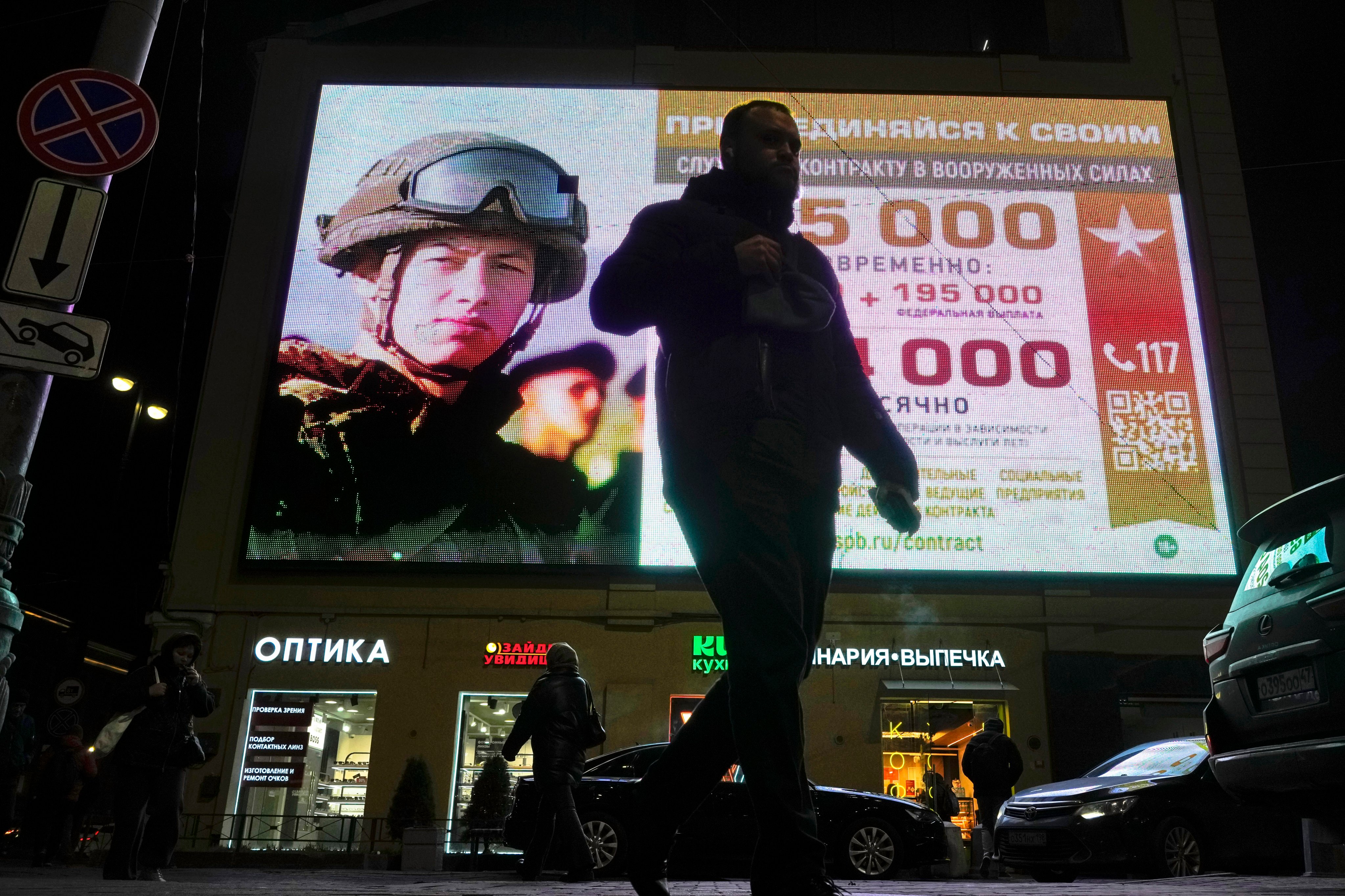 A man walks past an advertising screen depicting Russian army soldiers and promoting contract military service in the Russian army in St Petersburg, Russia on Monday. Photo: AP