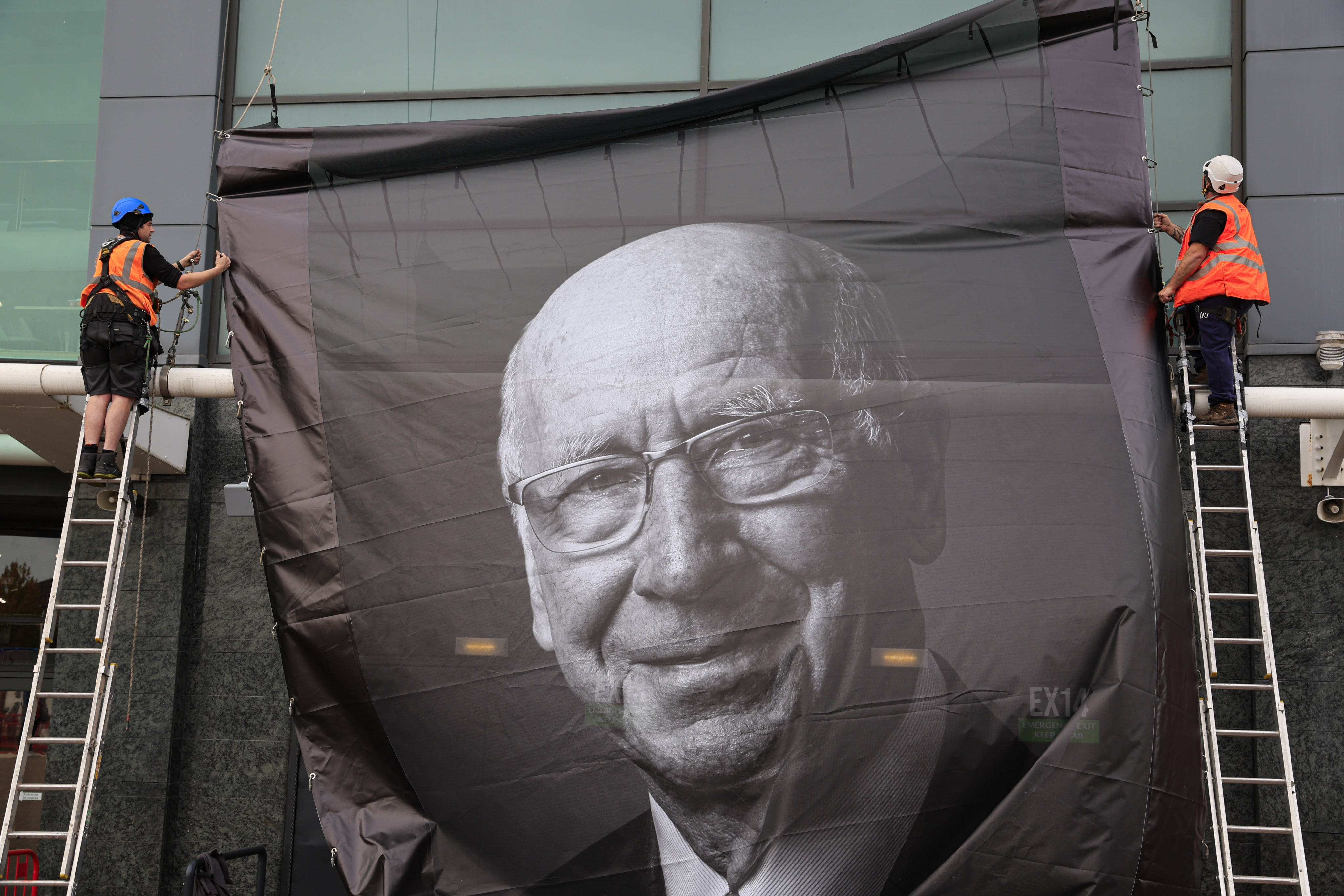 Workers place a memorial poster to the late Sir Bobby Charlton outside Old Trafford. Photo: dpa