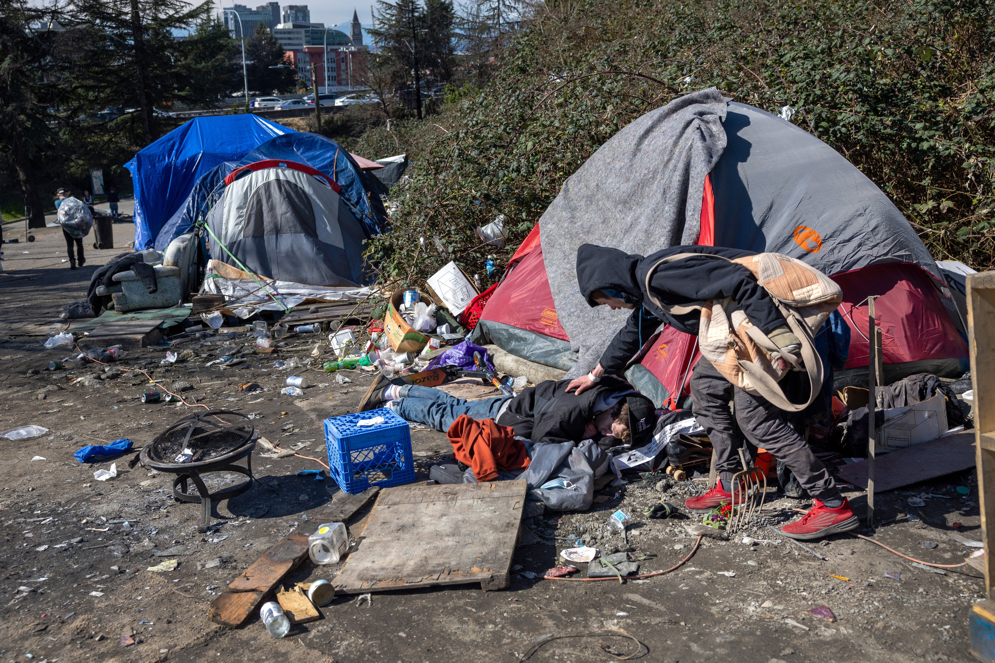 A homeless man checks on a friend who passed out after smoking fentanyl at a homeless encampment in Seattle, Washington, on March 12, 2022. Photo: AFP