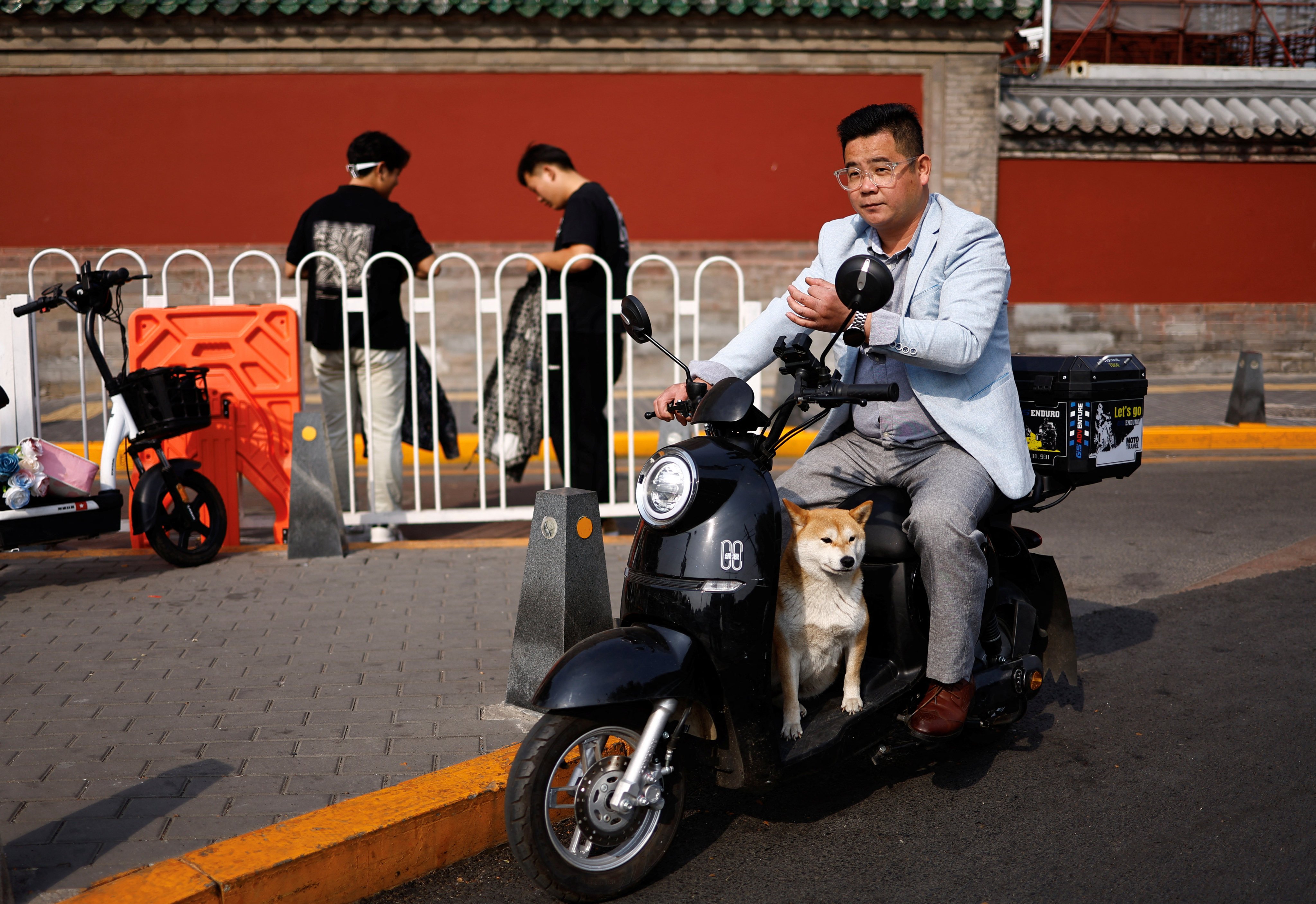 A man rides a scooter with a dog in Beijing on October 17. Raising a pet dog has become a way of life in China. Photo: Reuters 