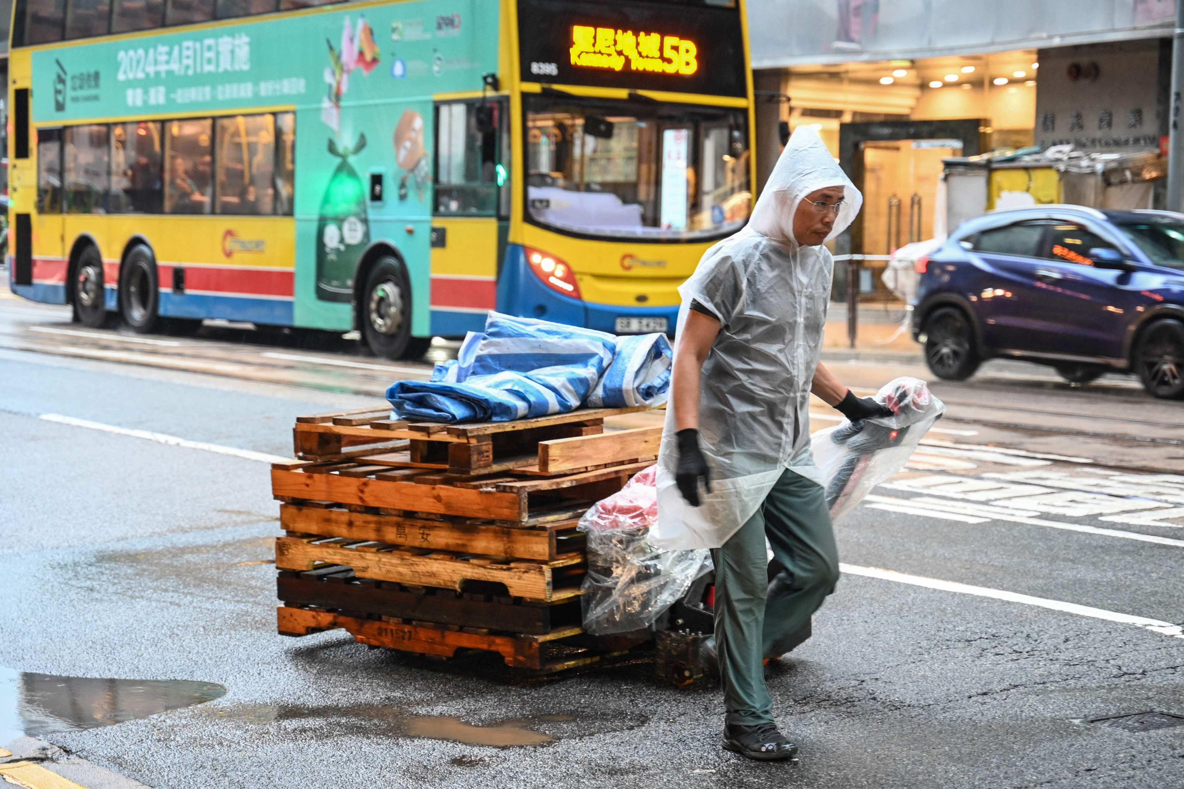 A delivery worker pulls pallets up a street in the rain in Hong Kong on October 18, 2023. (Photo by Peter PARKS / AFP)