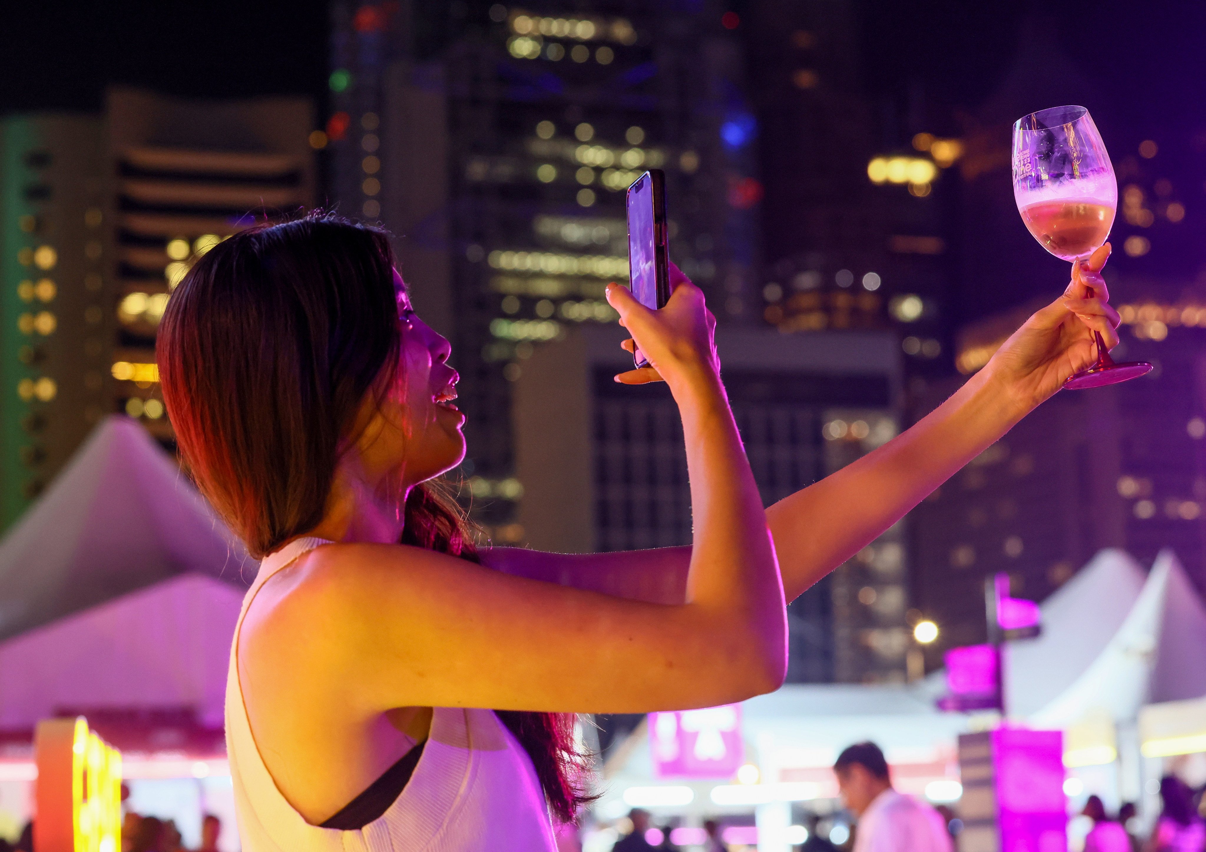 A woman takes a photo of her glass of wine at the Hong Kong Wine and Dine Festival at the Central harbourfront on October 26. Winemakers are facing pressure on multiple fronts with climate change reducing crop yields and changing tastes among young people driving down consumption. Photo: Dickson Lee