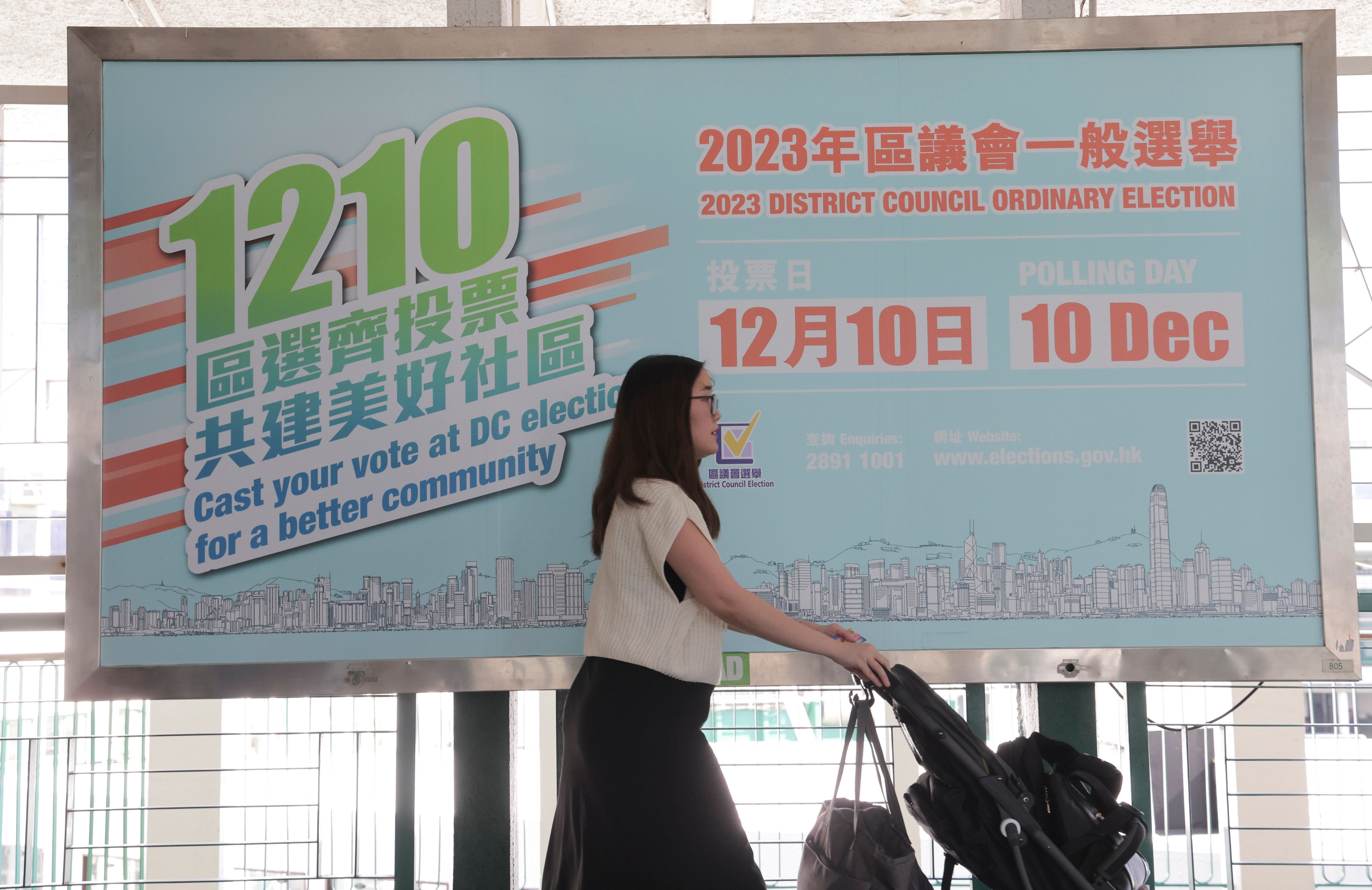 A pedestrian passes a large promotional poster for the 2023 district council elections, at Tsim Sha Tsui Pier on November 1. Centrists and the opposition have been all but frozen out of the upcoming election, leading to fears of reduced political diversity and representation. Photo: Jelly Tse