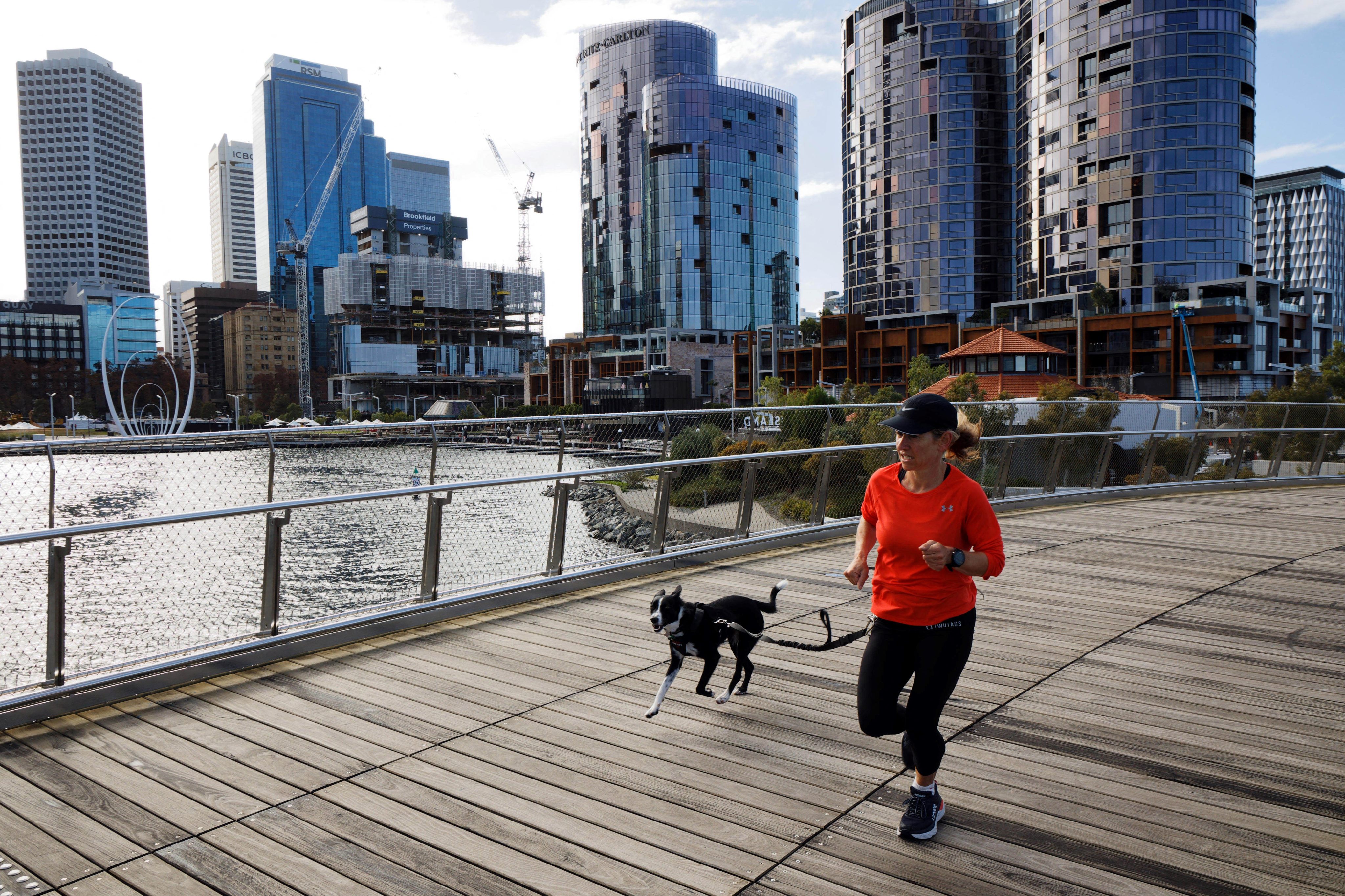 A woman runs with her dog through Elizabeth Quay in Perth in 2021. An acute rental affordability crisis –particularly in Perth, Brisbane, Sydney and Melbourne – has become a hot-button social and political issue. Photo: AFP 
