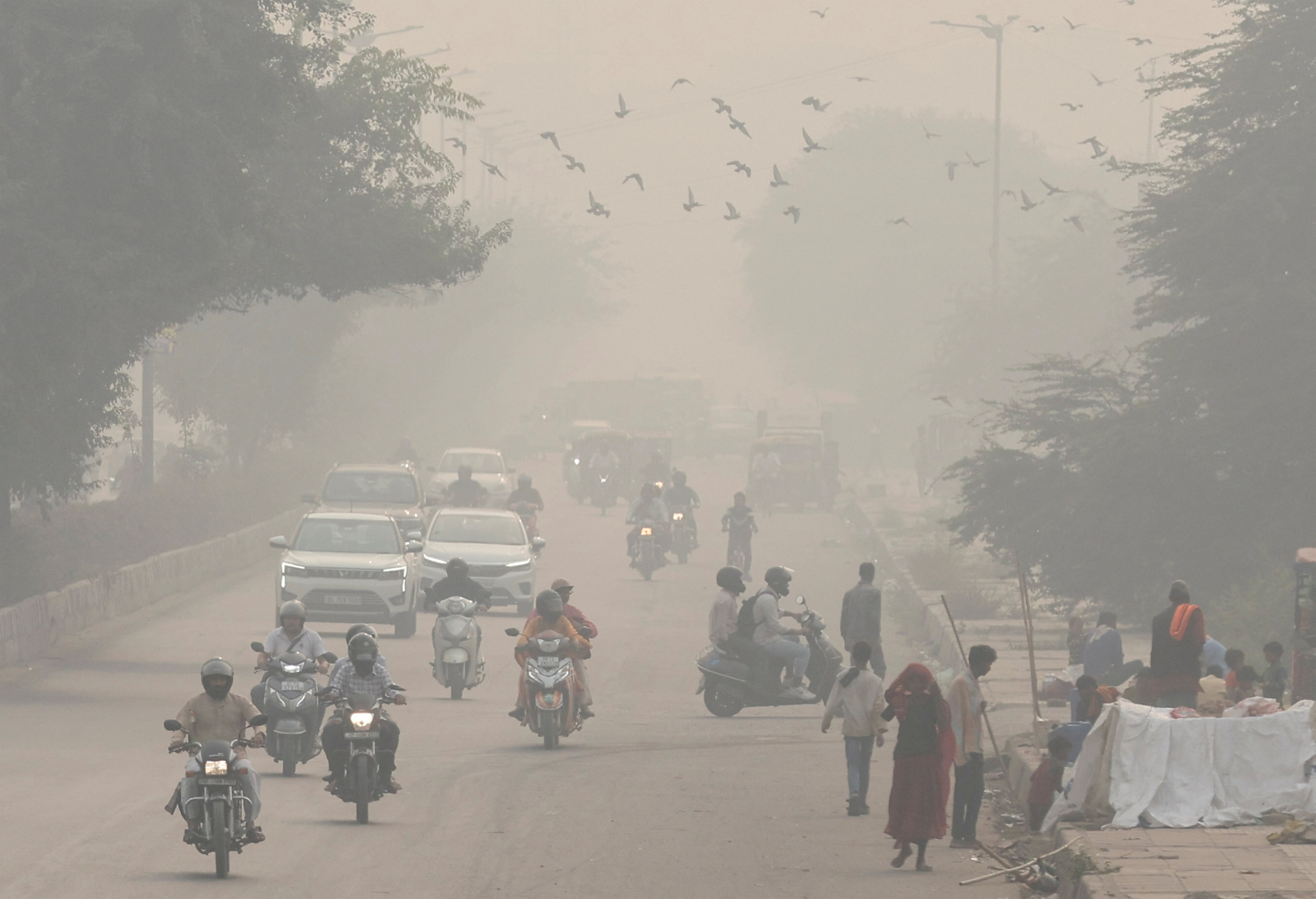 People and vehicles are seen on a road amid the morning smog in New Delhi, India, on Wednesday. Photo: Reuters