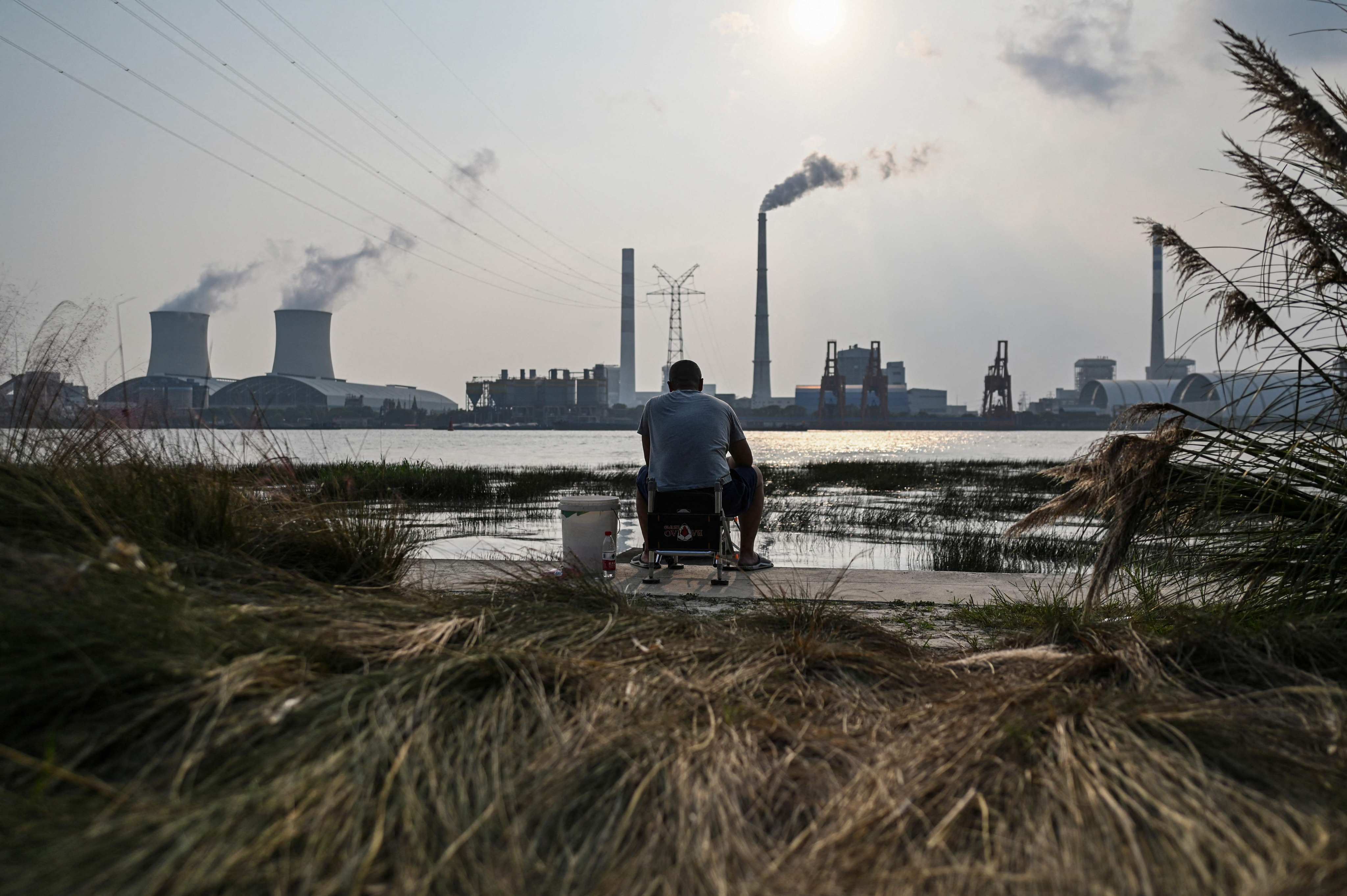An angler is seen fishing along the Huangpu river across from the Wujing Coal-Electricity Power Station in Shanghai on September 28, 2021. Photo: AFP