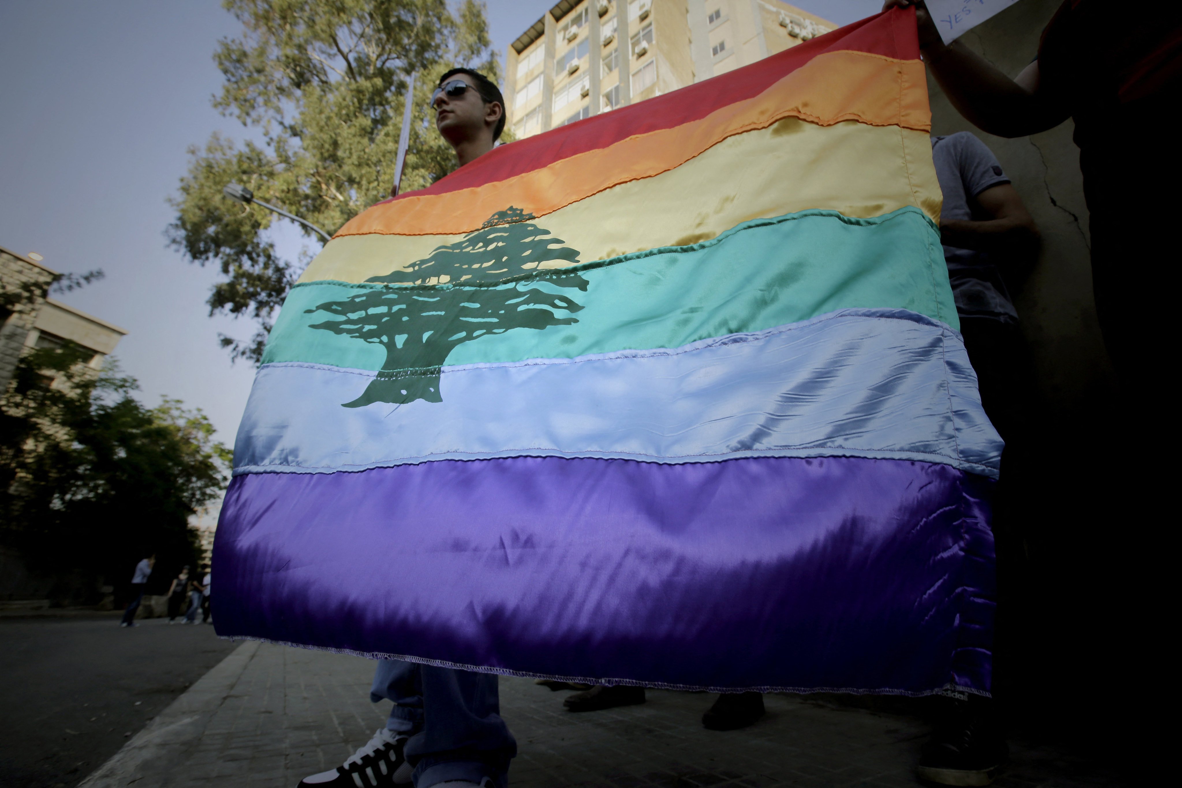 A gay pride flag bearing the cedar tree in the middle of it is carried by human rights activists during an anti-homophobia rally in Beirut on April 30, 2013. Lebanese homosexuals, human rights activists and members from the NGO Helem (the Arabic acronym of “Lebanese Protection for Lesbians, Gays, Bisexuals and Transgenders”) rallied to condemn the arrest on the weekend of three gay men and one transgender civilian in the town of Dekwaneh east of Beirut at a nightclub who were allegedly verbally and sexually harassed at the municipality headquarters. AFP PHOTO/JOSEPH EID (Photo by Joseph EID / AFP)