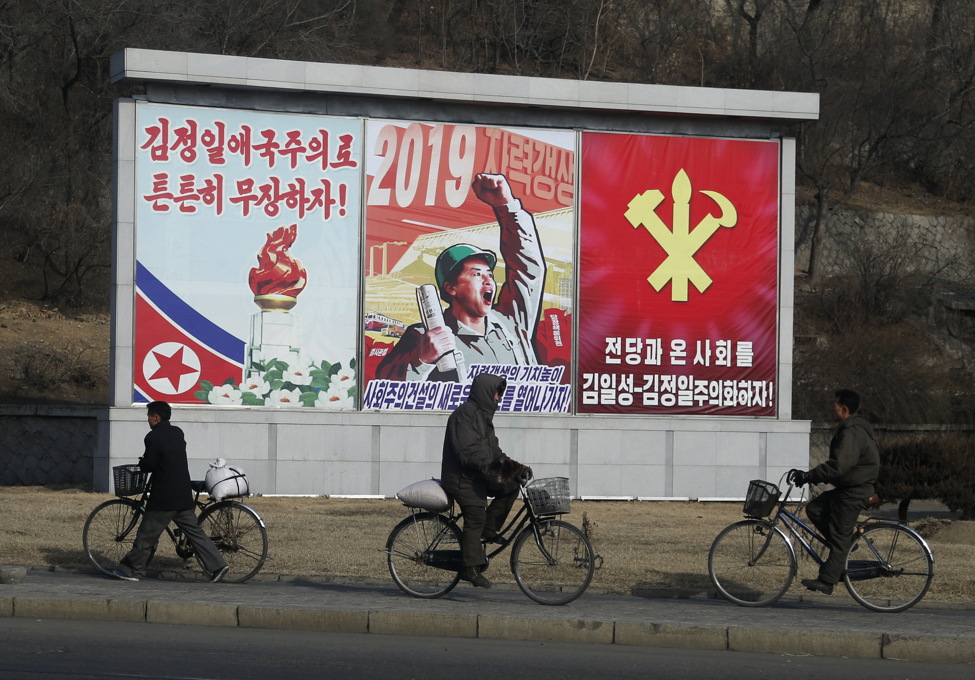 North Korean men ride their bicycles past propaganda banners in Pyongyang. Photo: AP