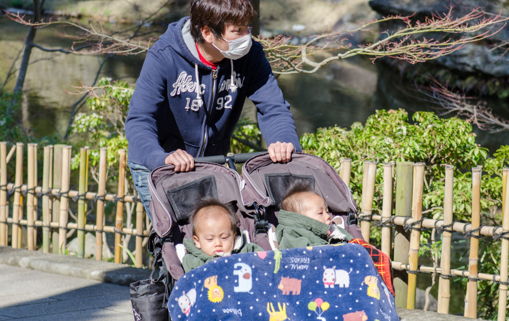 A young father takes a walk with his twin children in Japan. Photo: Shutterstock