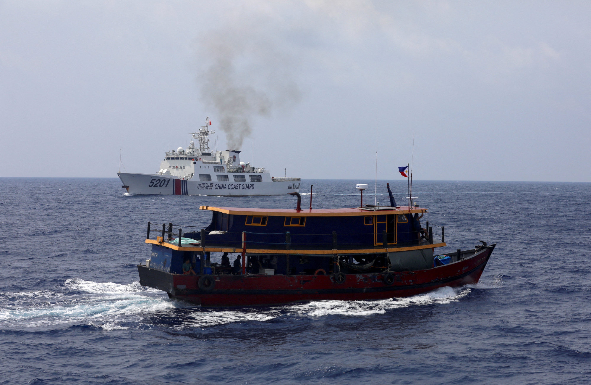 A Philippine supply boat (foreground) sails near a Chinese coastguard ship during a resupply mission for Philippine troops stationed at a grounded warship in the South China Sea on Oct. 4. Photo: Reuters