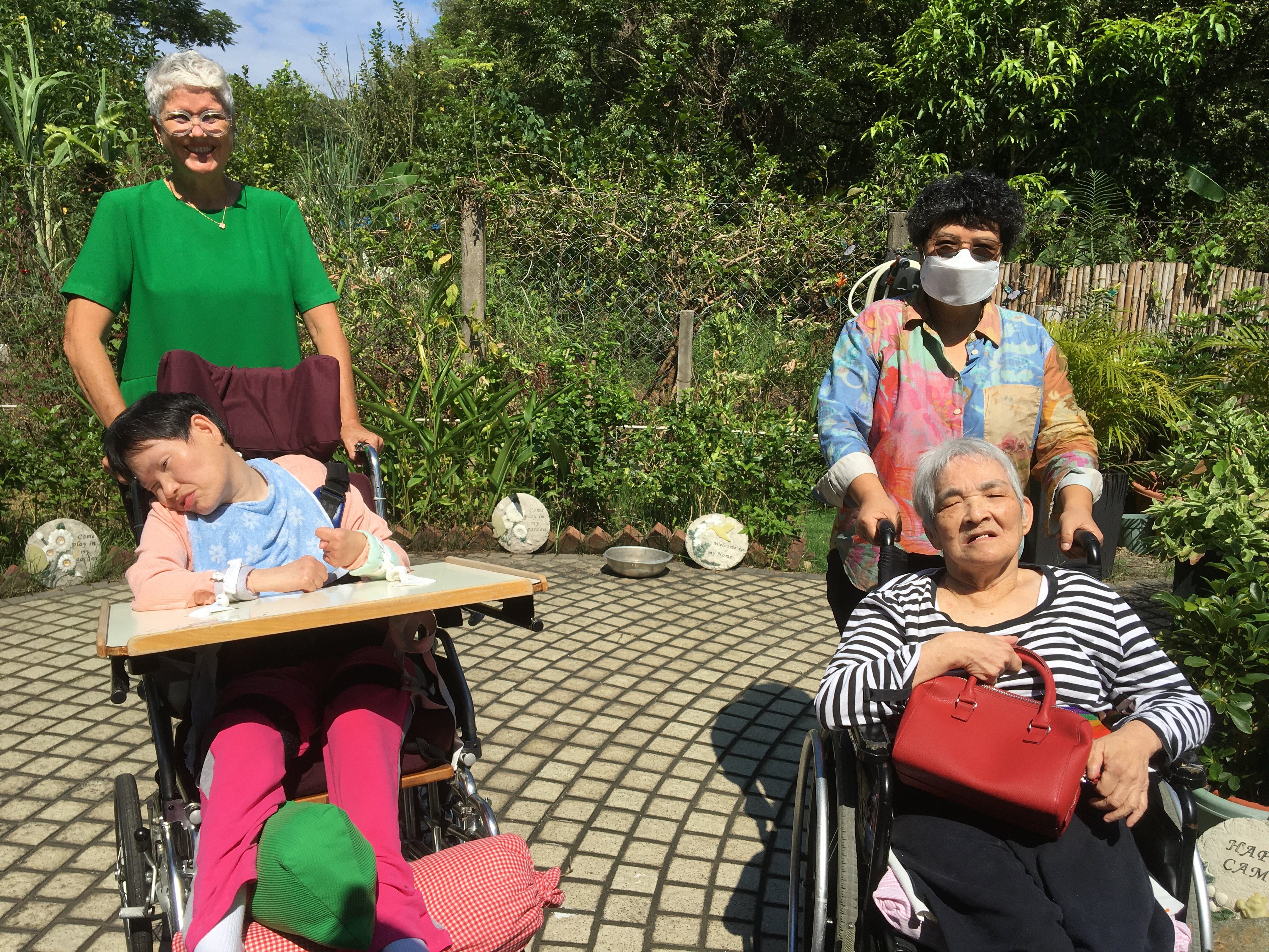 HOLF’s acting coordinating superintendent Gretchen Ryan (left) and senior manager Wenda Wong take residents for a stroll in the garden after lunch. Photo: Cindy Sui