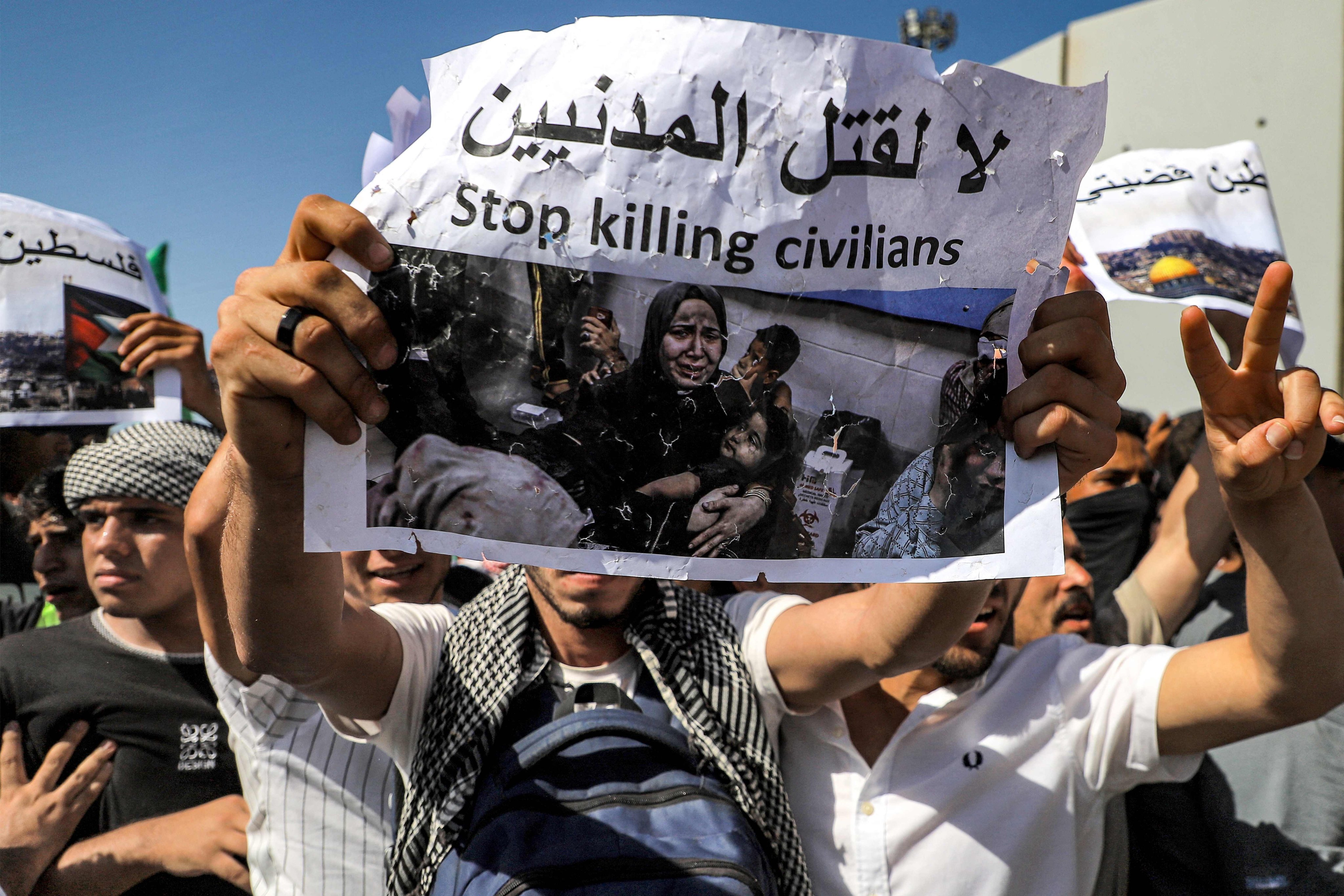 Protesters on the Egyptian side of the Rafah border crossing with Gaza hold placards denouncing the killing of civilians during a rally at the site last month. Photo: AFP