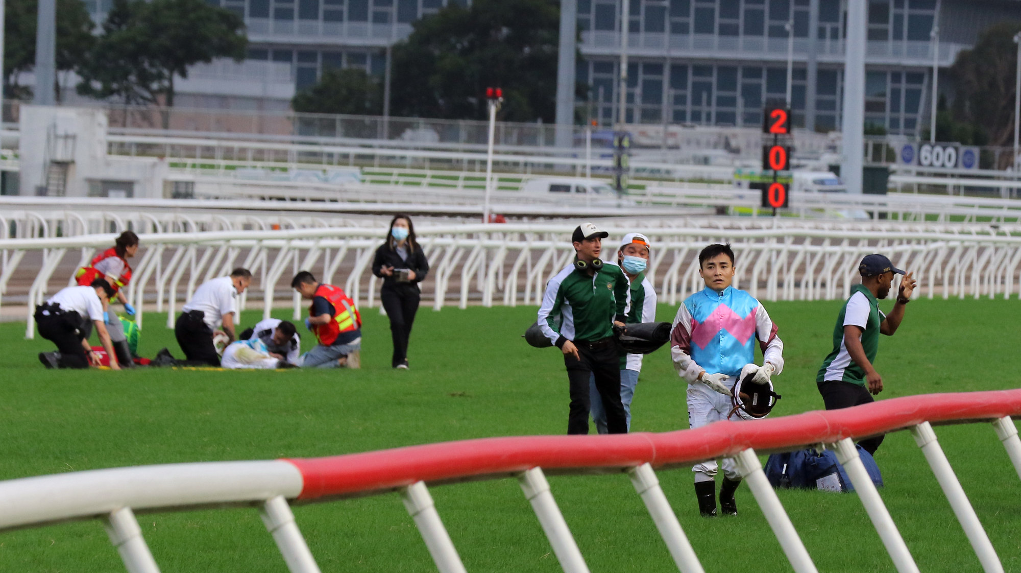 Keith Yeung walks away while Hugh Bowman is treated on the track at Sha Tin on Saturday.