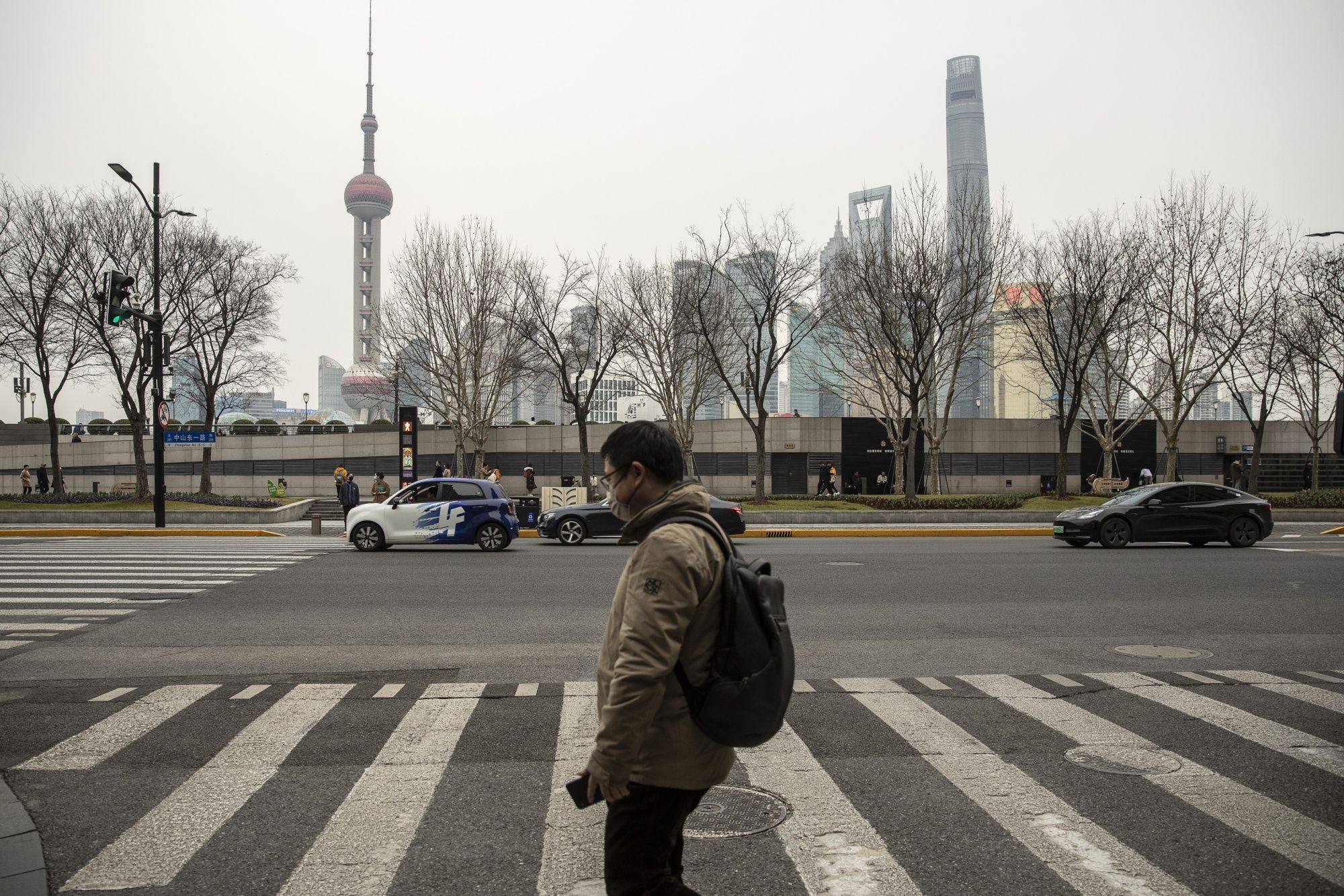 A pedestrian crosses a street near the Bund across from buildings in Pudong’s Lujiazui financial district in Shanghai, on February 28, 2023. Photo: Bloomberg