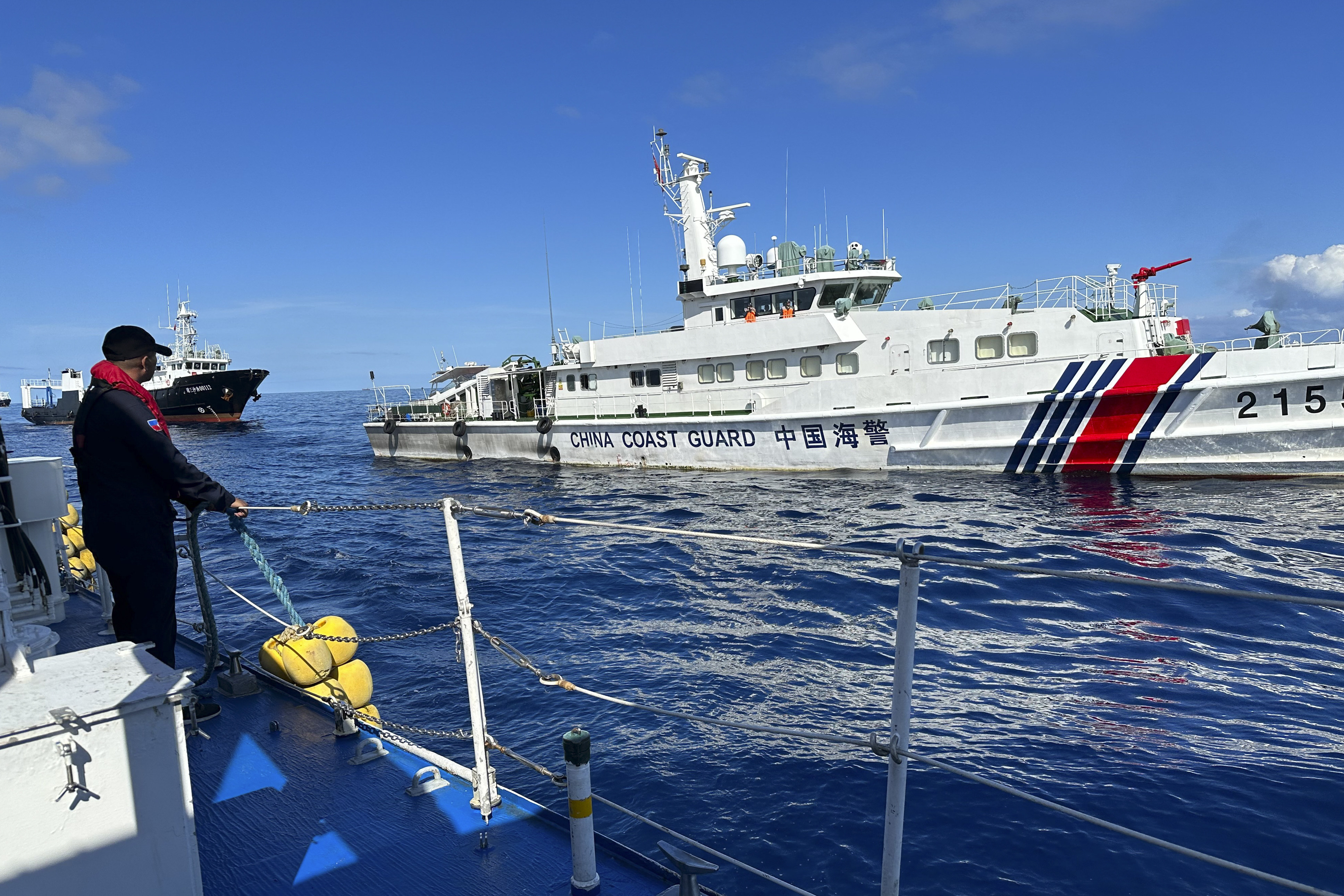 A Philippine Coast Guard member holds on a rubber fender as a Chinese coast guard vessel and suspected Chinese militia ship chases the BRP Cabra while approaching Second Thomas Shoal on November 10. Photo: AP