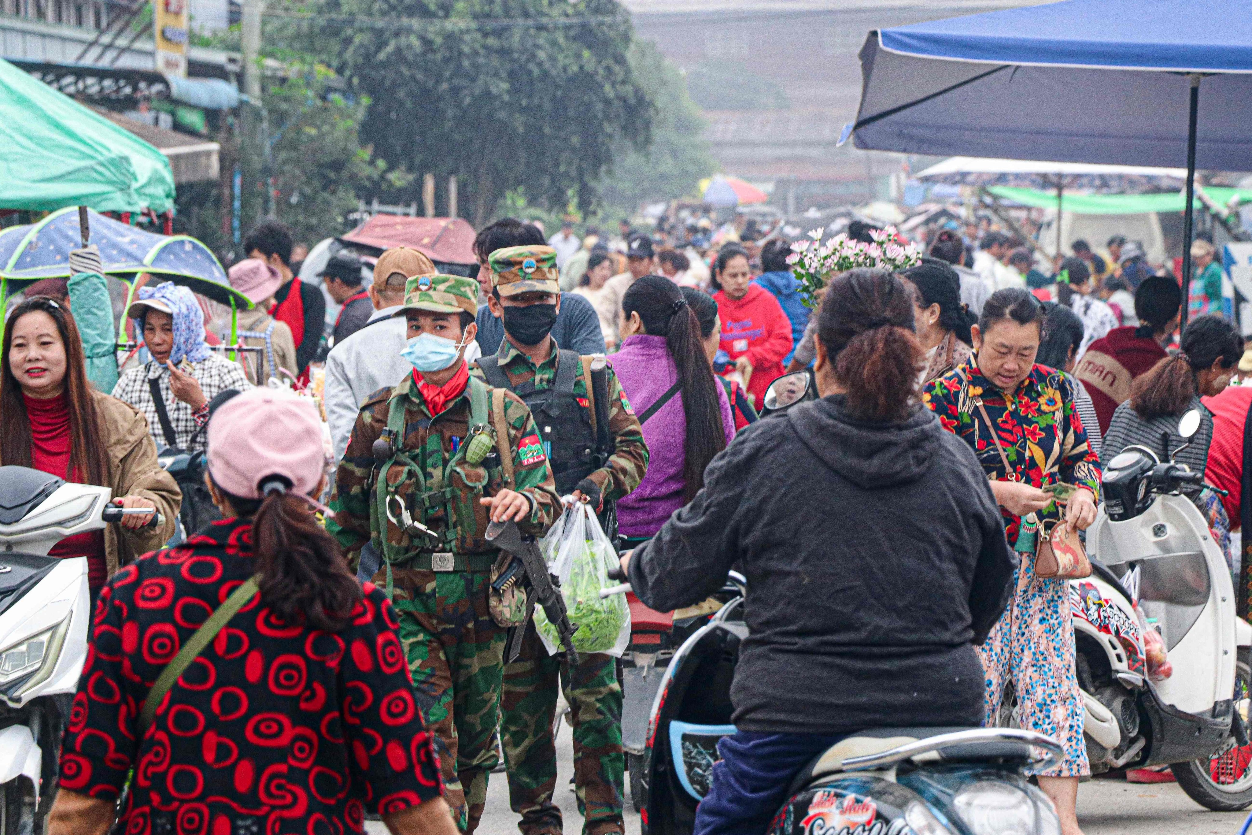 Fighters of the ethnic rebel group Ta’ang National Liberation Army walk down a street market in the town of Namhkam in northern Shan state on Friday. Photo: AFP