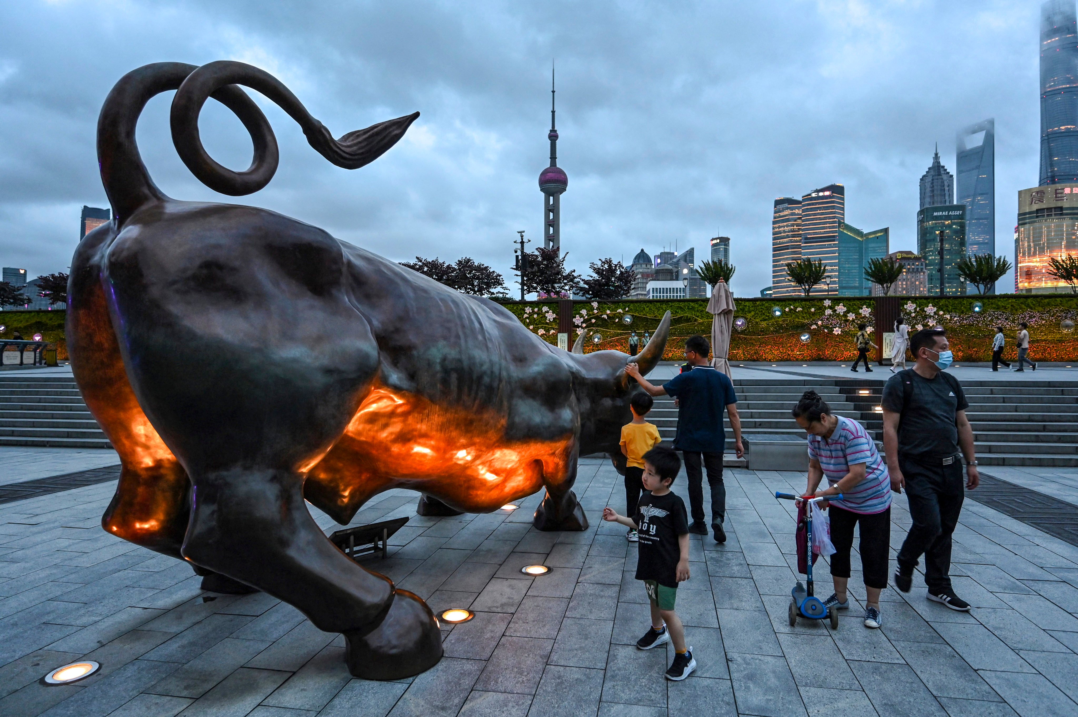 This photo taken on June 9, 2021 shows people standing next to the Bund Bull sculpture in Shanghai. Photo: AFP