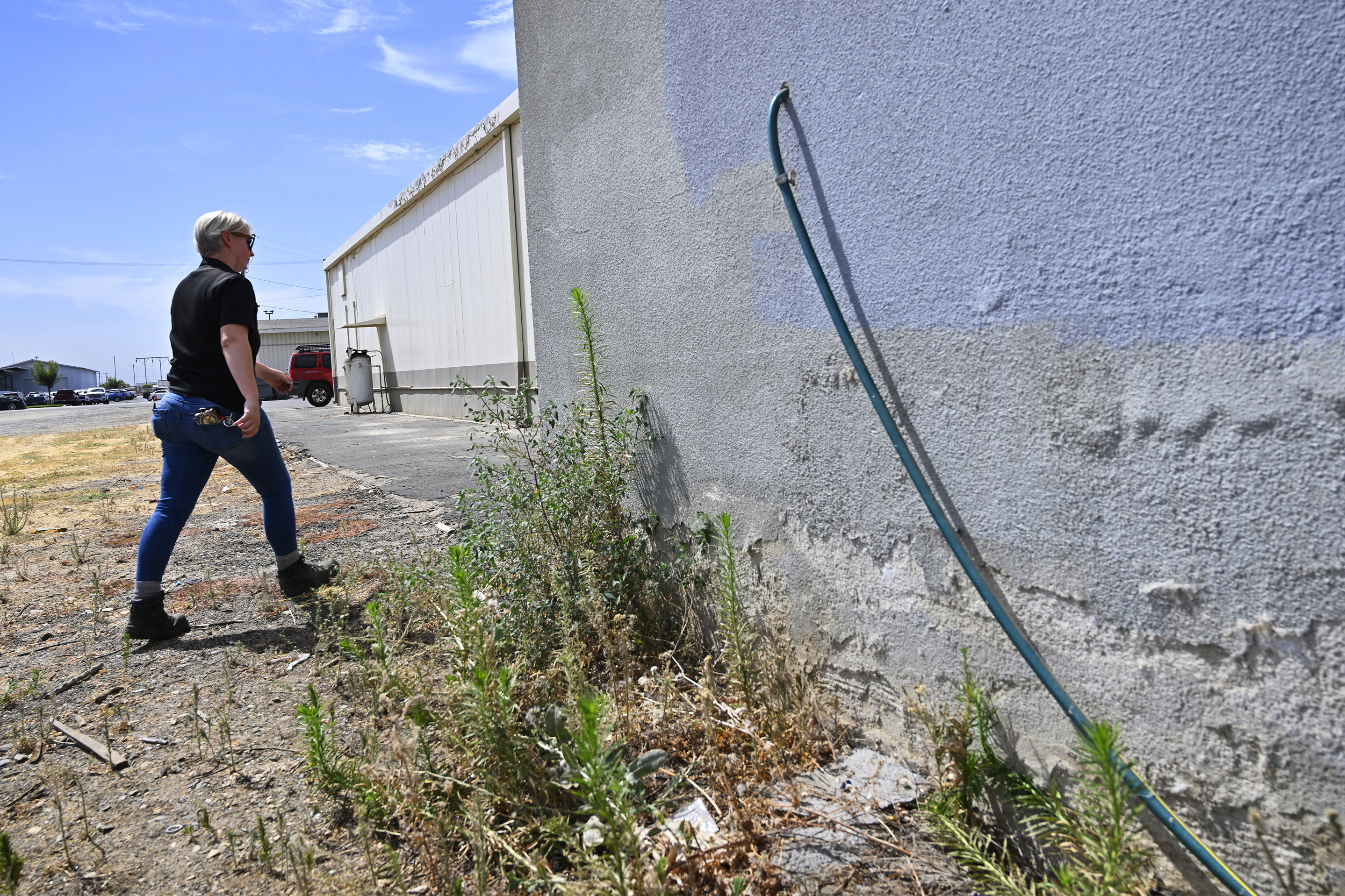 Code enforcement officer Jesalyn Harper walks past the garden hose that tipped her off to an illegal medical lab operating in Reedley, California, on Aug. 1. Photo: The Fresno Bee via AP