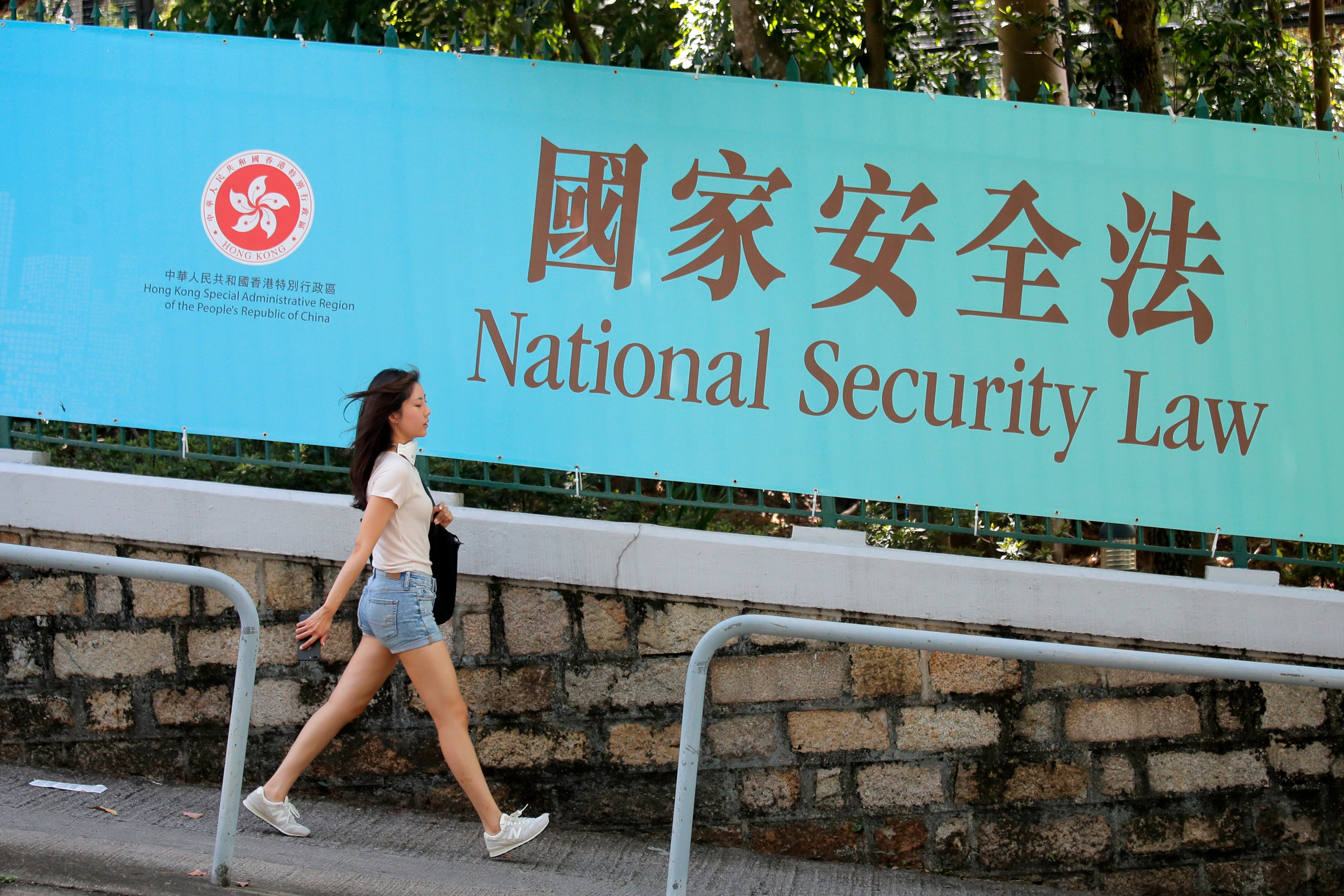 A woman walks past a banner promoting the national security law for Hong Kong in 2020. Three years after the law was imposed, uncertainty lingers over the impending Article 23 legislation. Photo: AP 