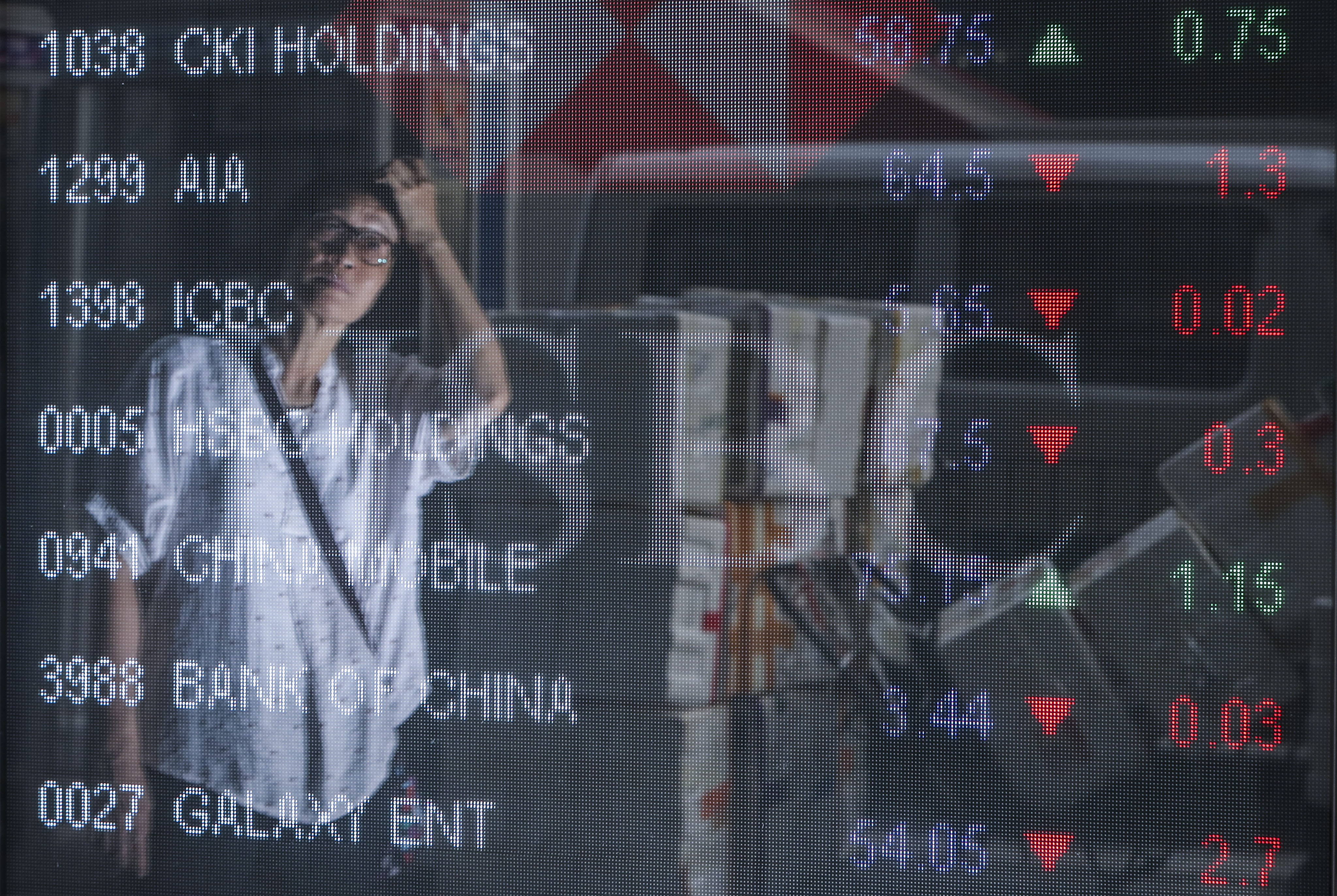 A pedestrian looks at the electronic screen displaying Hang Seng Index stocks outside a bank in Mong Kok, Hong Kong. Photo: Winson Wong