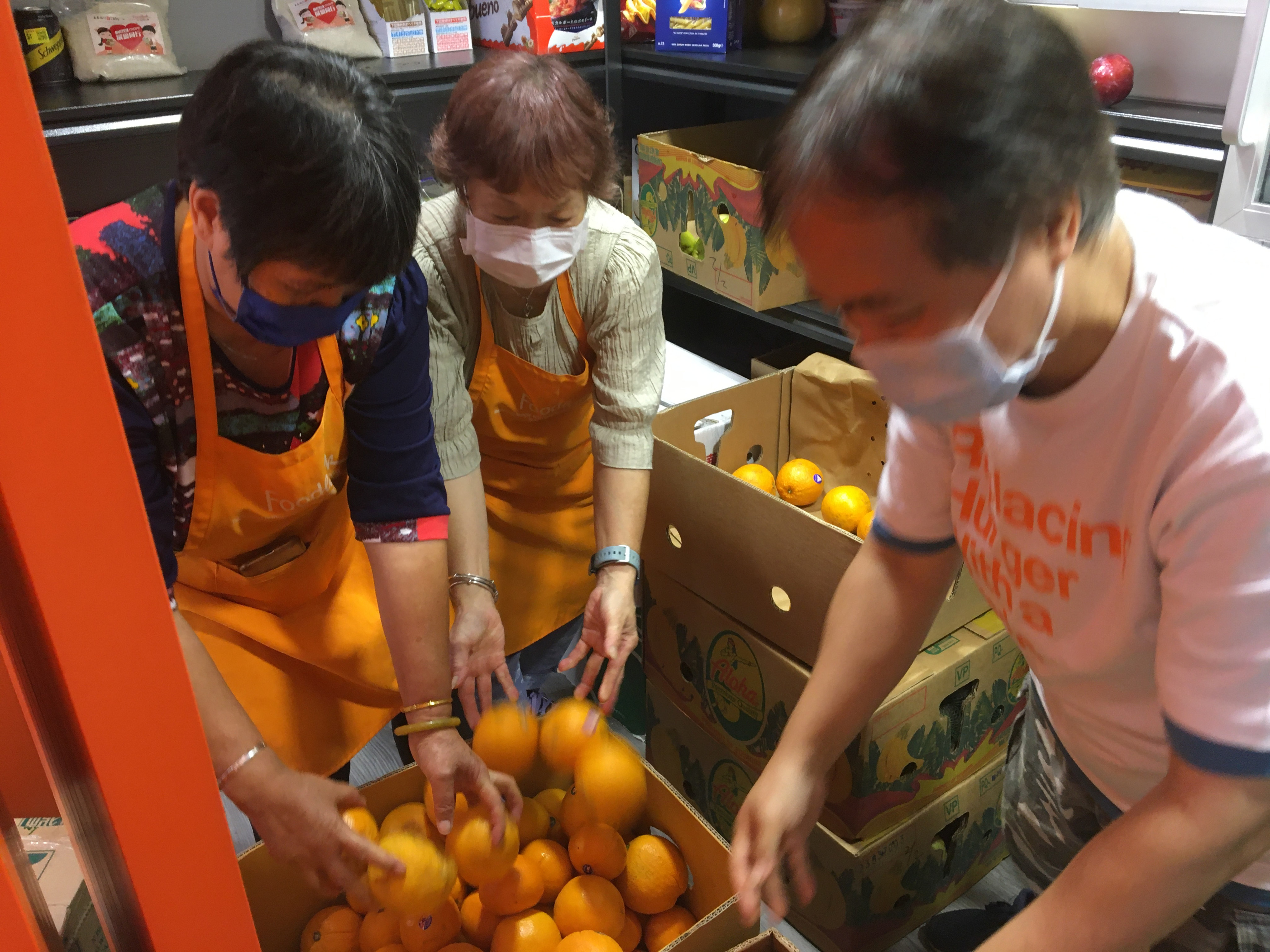 Foodlink Mart’s store manager (right) and two elderly beneficiaries, who are also volunteers, sort fruits delivered to the store from supermarkets. Photo: Cindy Sui