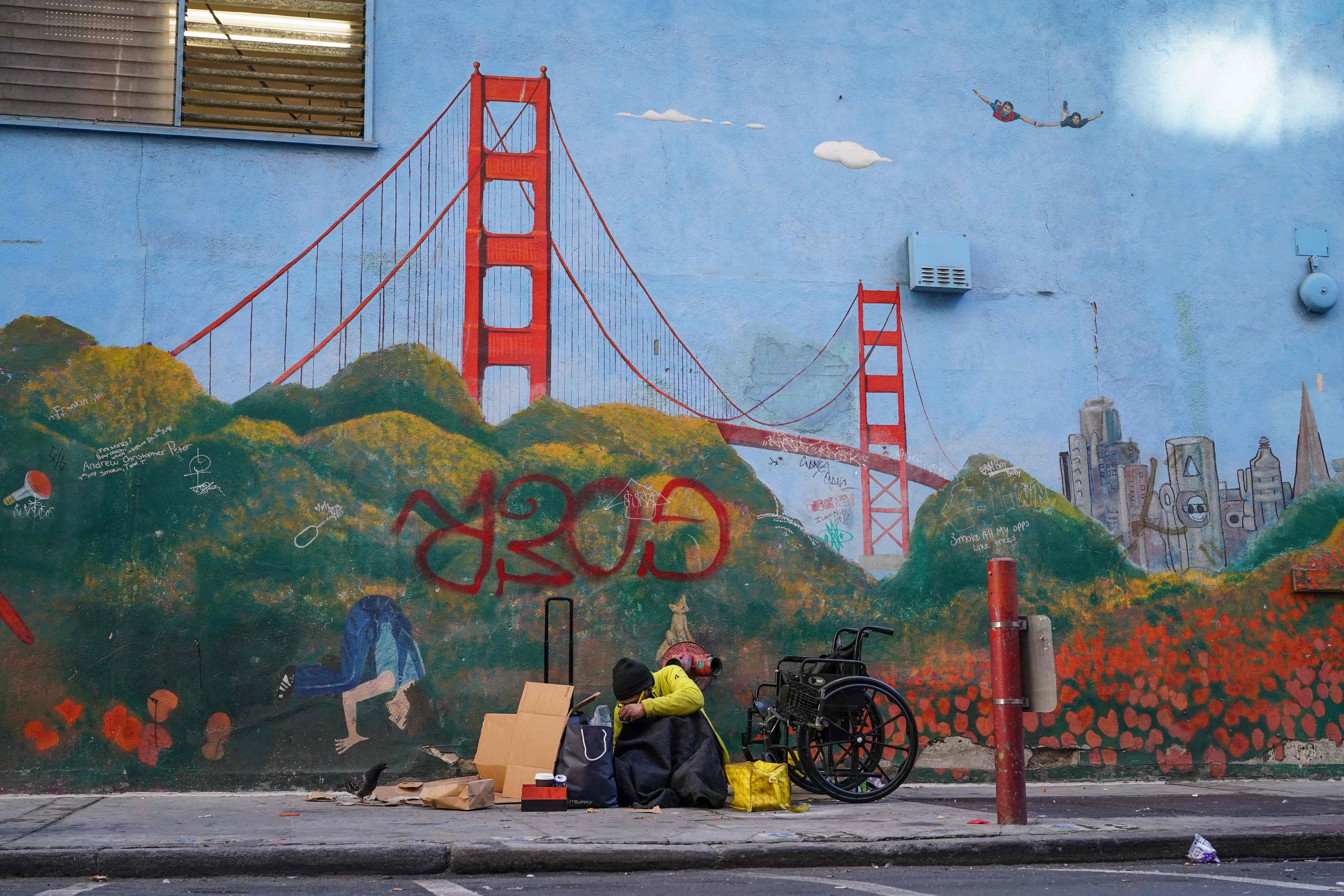 A homeless person in San Francisco sits by a mural of the city’s famed Golden Gate Bridge. Photo: AFP