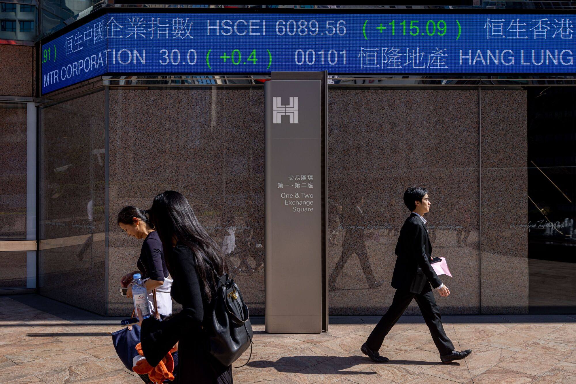 Pedestrians walk past the electronic ticker displaying stock figures at the Exchange Square Complex, which houses the Hong Kong stock exchange, on November 20, 2023. Photo: Bloomberg
