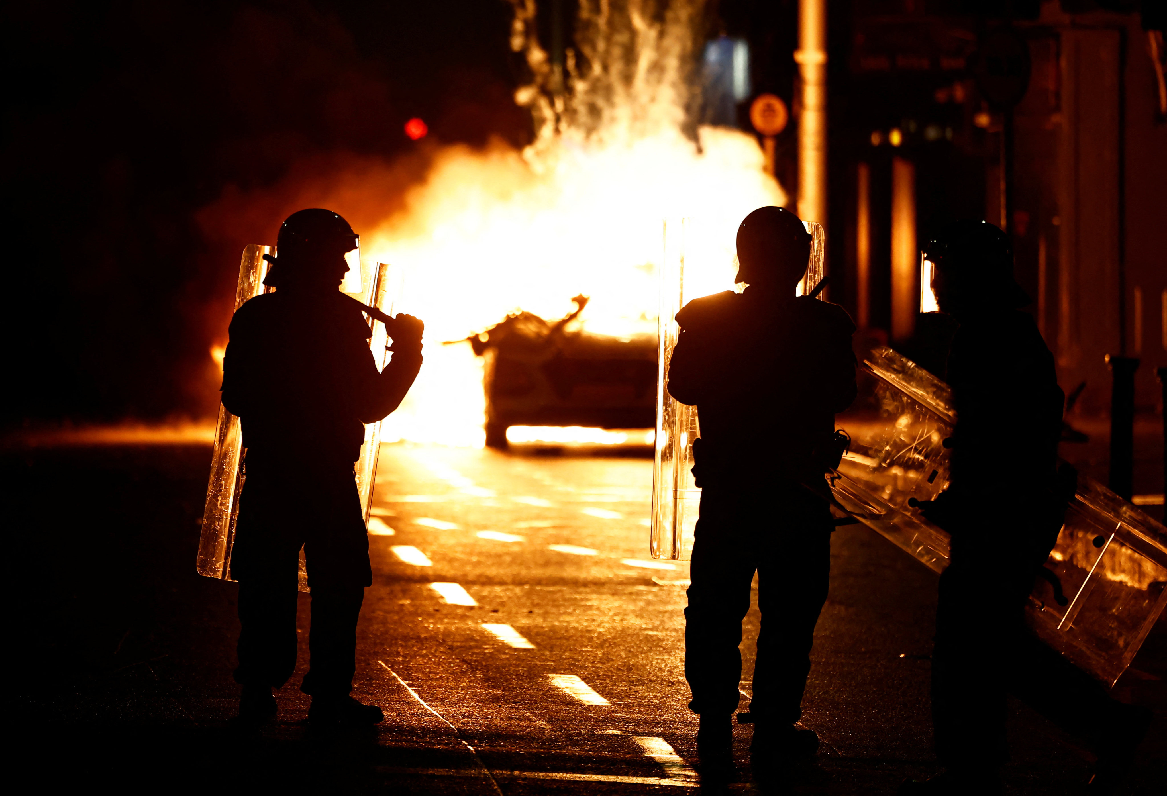 Riot police stand next to a burning police vehicle in Dublin, Ireland on Thursday. Photo: Reuters