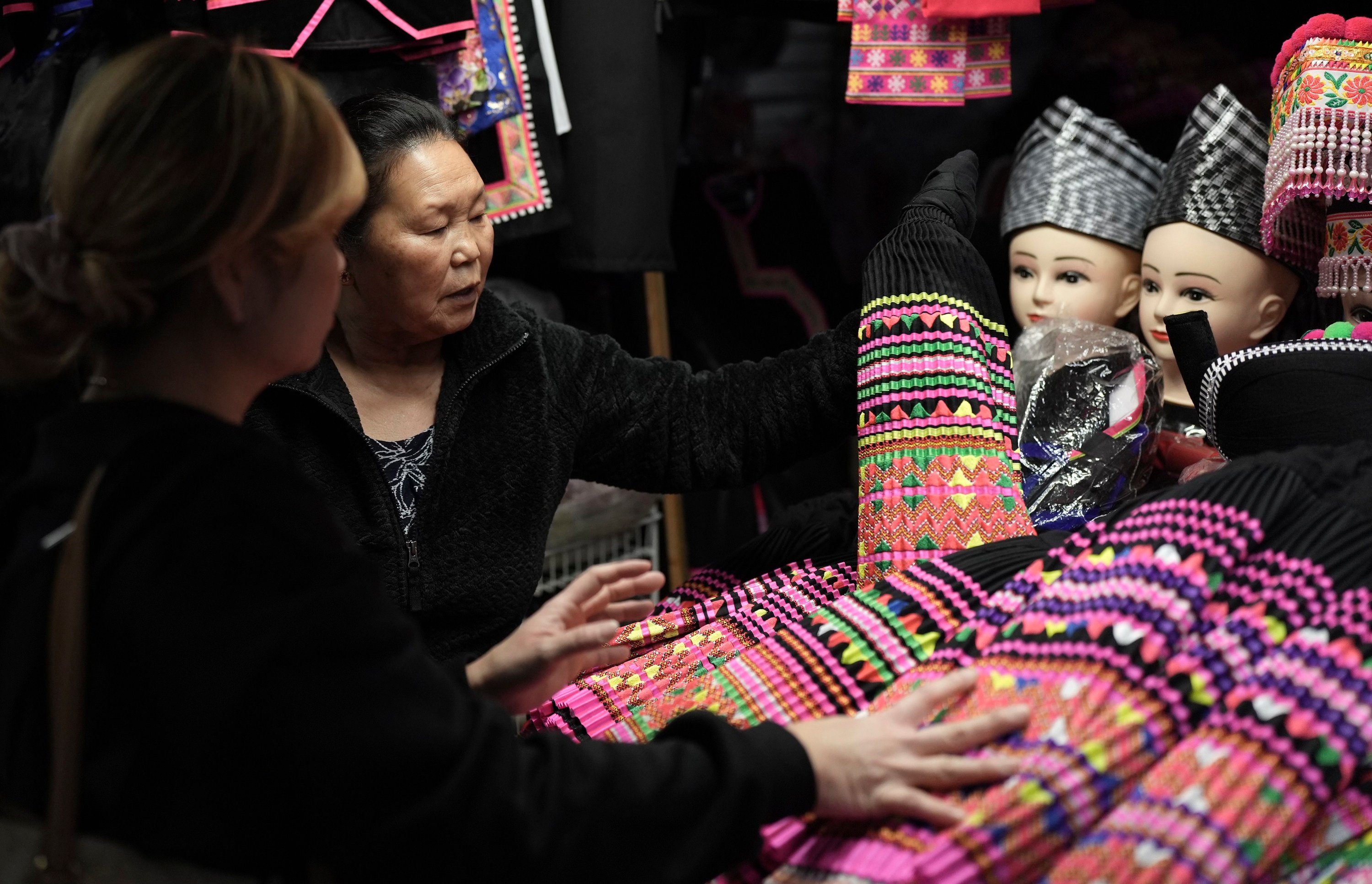 Shoppers look for pleated skirts and other clothing for Hmong New Year for sale at the stall of Elisa Her, left, in the Hmong Village covered market in St Paul, Minnesota. The New Year, celebrated at various dates in autumn by Hmong Americans, is the most important traditional spiritual celebration for these Southeast Asian refugees who settled in the United States after fighting on its side in the Vietnam War. Photo: AP