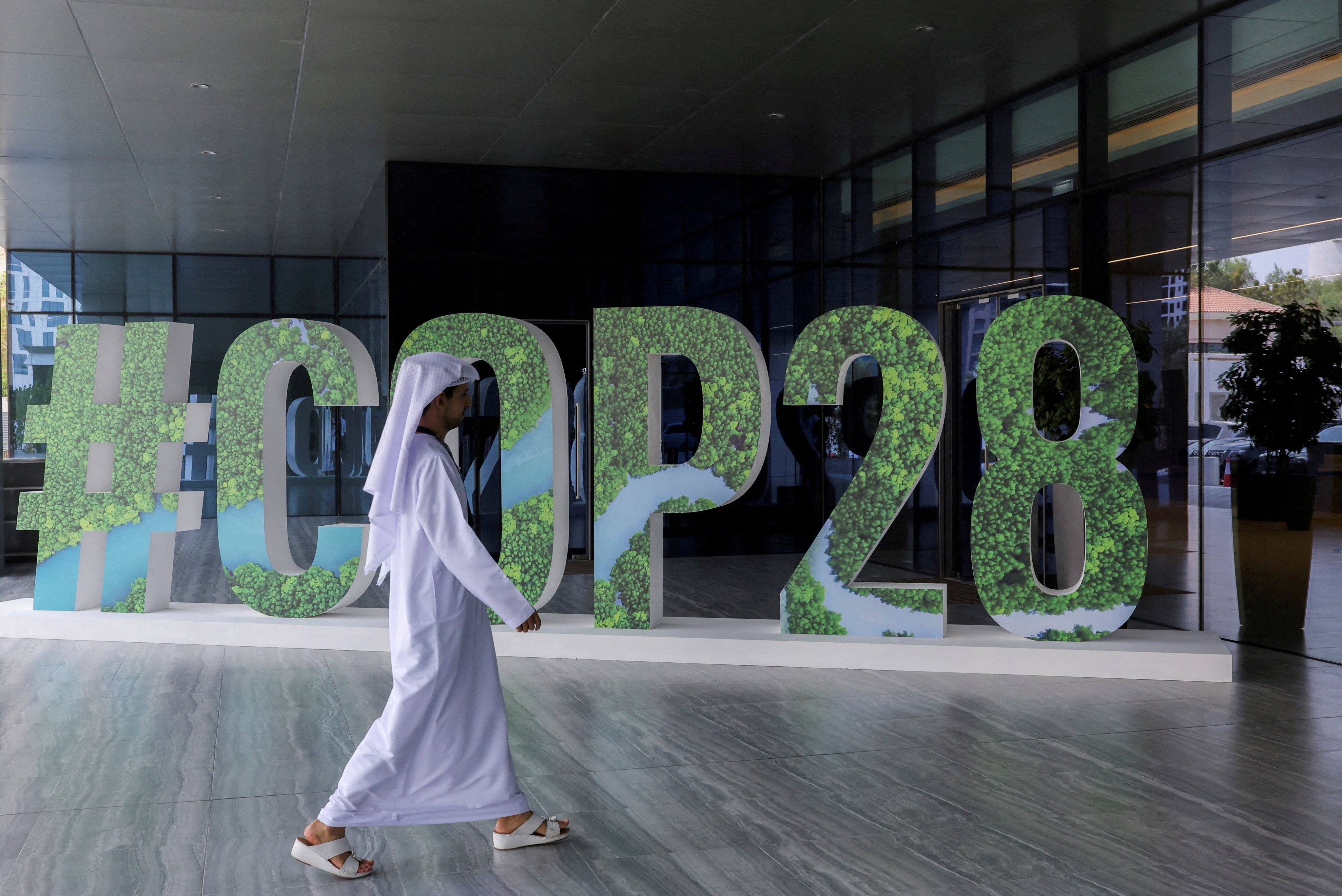 A man walks past a “#COP28” sign in Abu Dhabi. Over 60 countries have already agreed to back the deal, spearheaded by the European Union, United States and United Arab Emirates, to triple renewable energy this decade ahead of the summit. Photo: Reuters