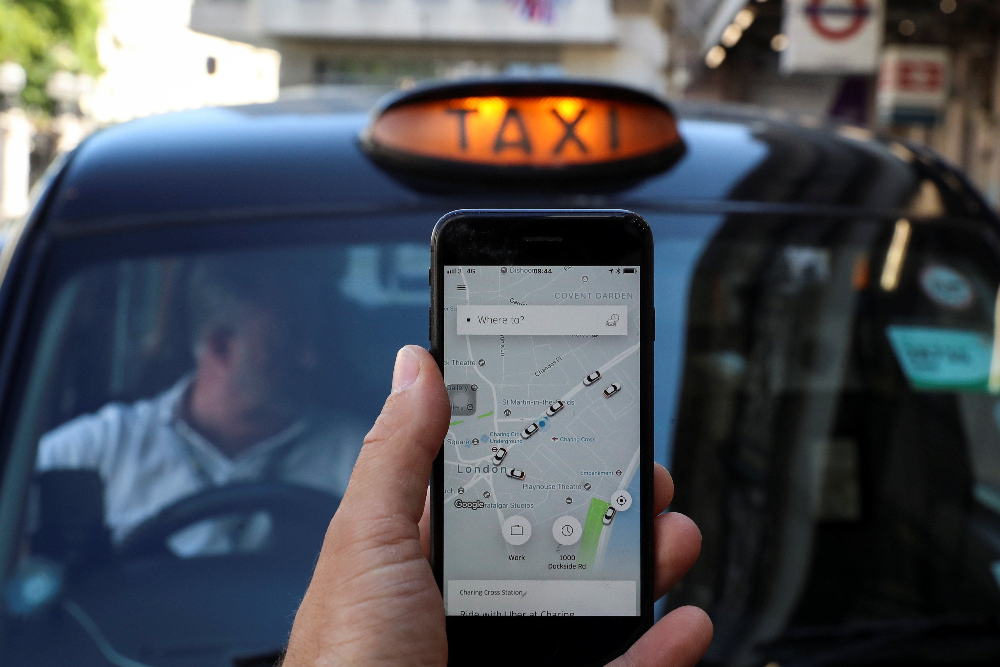 A photo illustration shows the Uber app and a black cab in London, June 26, 2018. Photo: Reuters