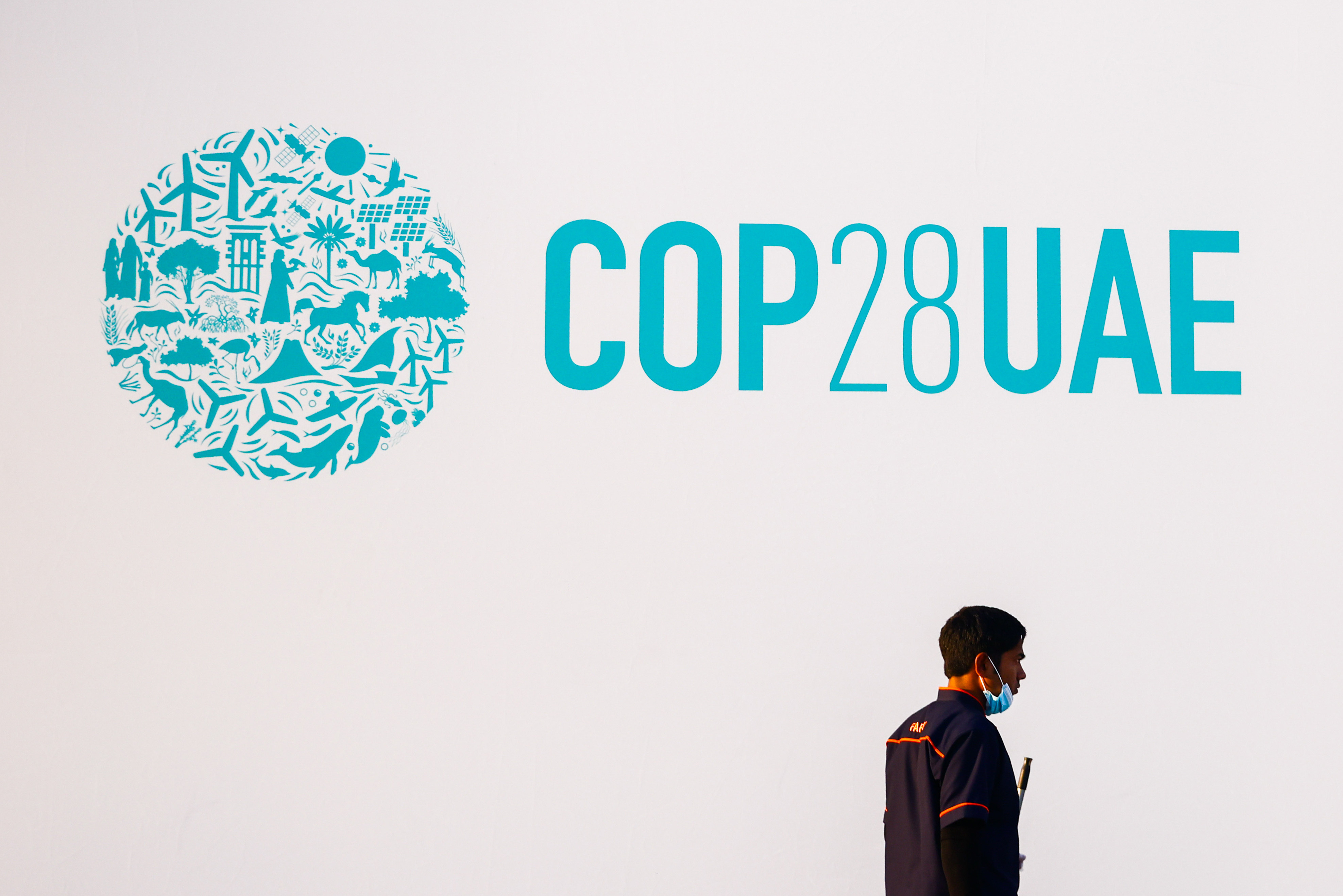 On November 27, 2023 in Expo City, Dubai, United Arab Emirates, a worker walks in front of the logo of 2023 United Nations Climate Change Conference (COP28), which takes place from November 30 through December 12. Photo: Zuma Press Wire