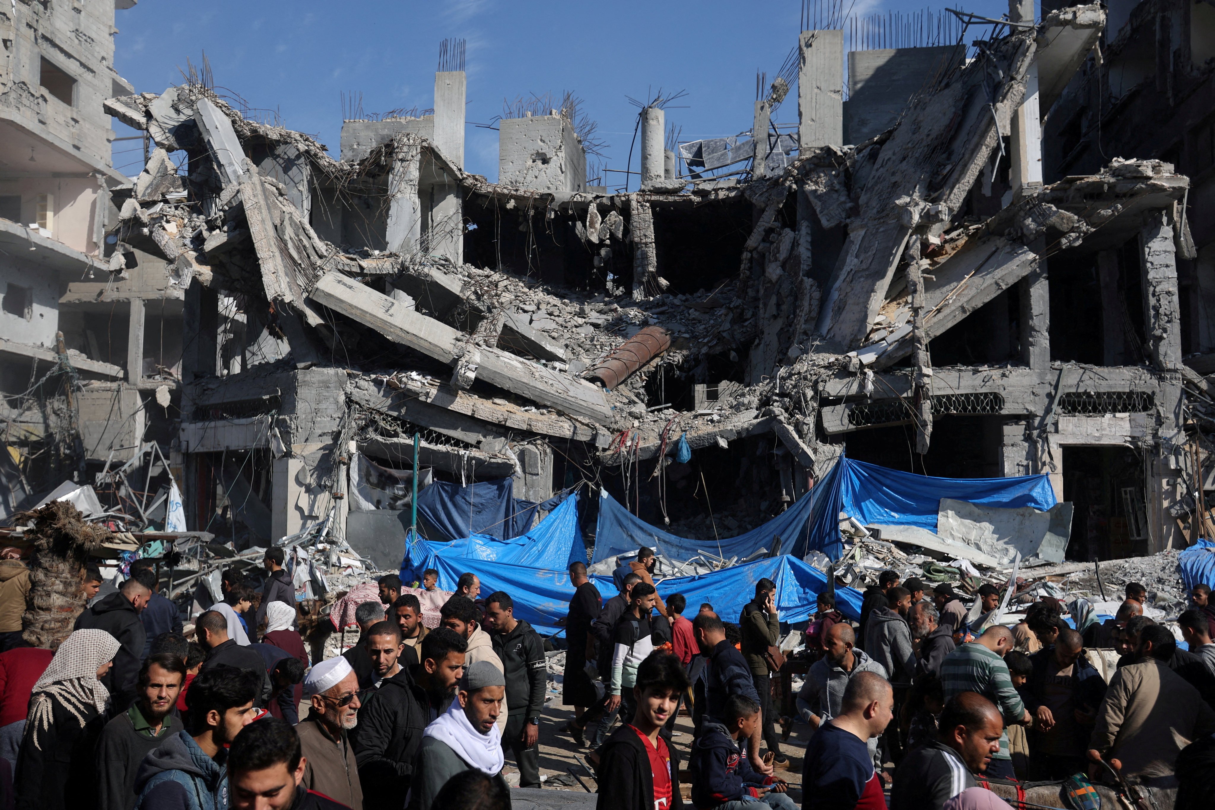 Palestinians shop on Thursday in an open-air market near the ruins of houses and buildings destroyed in Israeli strikes. Photo: Reuters
