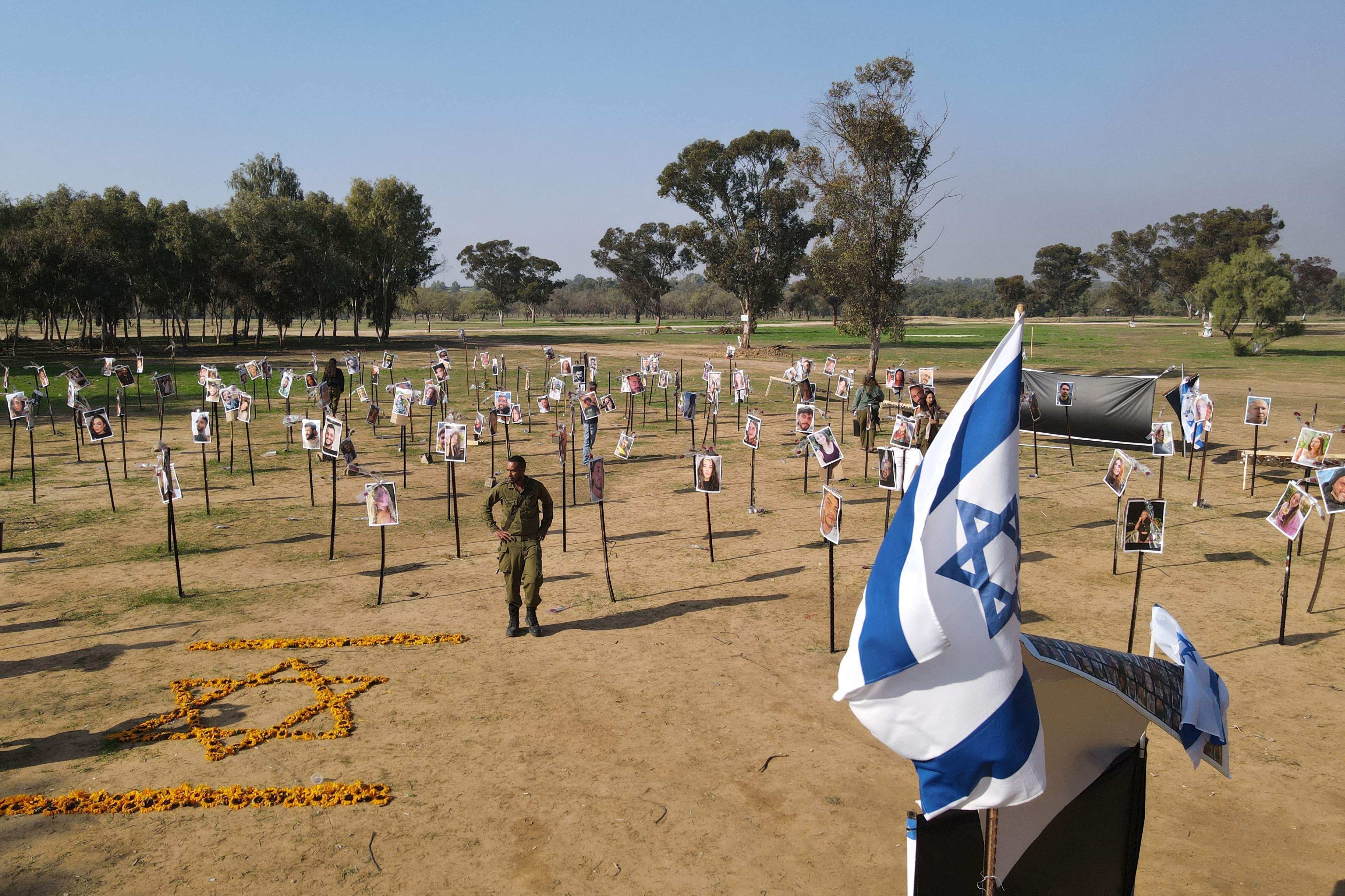 Israeli soldiers on Friday walk among the pictures of people taken captive or killed by Hamas militants duing the Supernova music festival on October 7. Photo: AFP