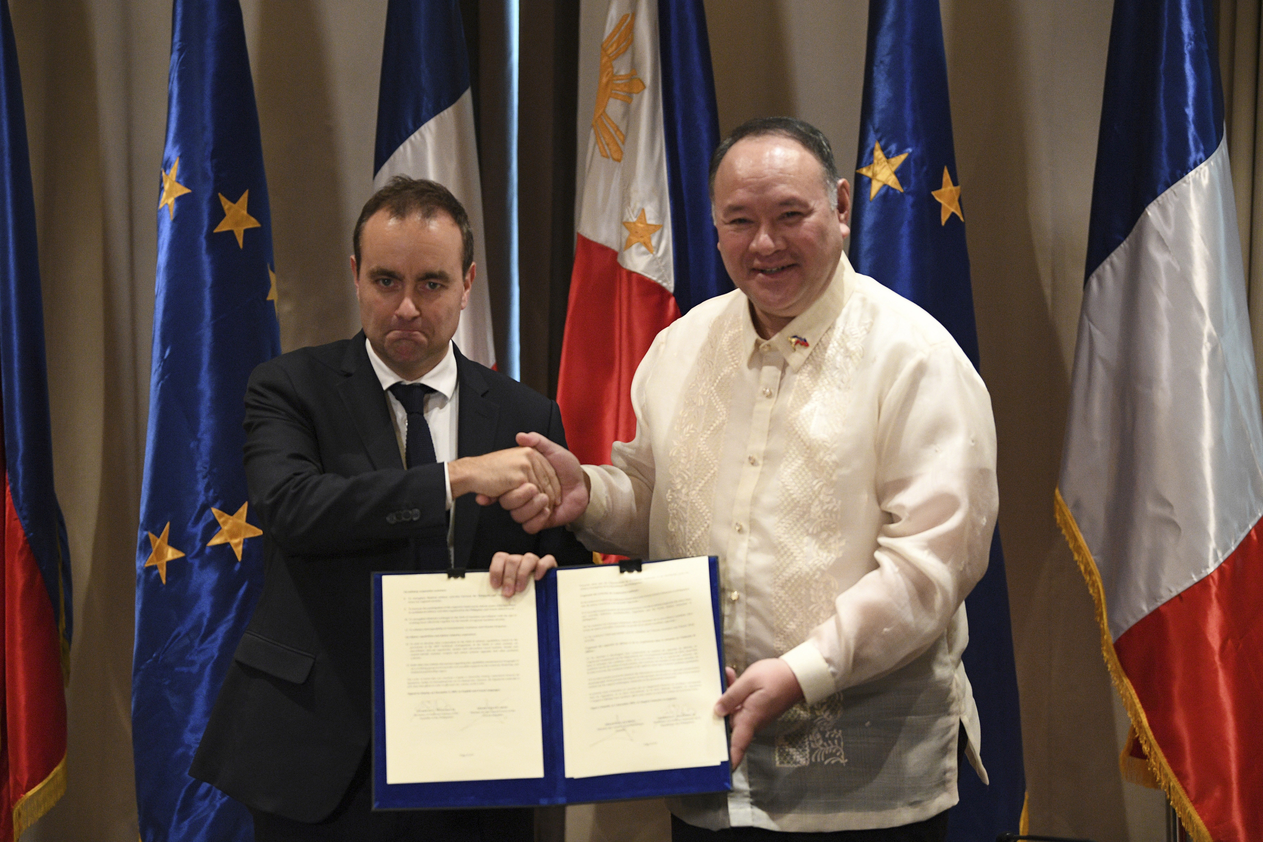 French Defence Minister Sebastien Lecornu (left) shakes hands with his Philippine counterpart Secretary Gilberto Teodoro as they hold a document during a joint press conference at a hotel in Manila, Philippines on Saturday. Photo: Pool via AP