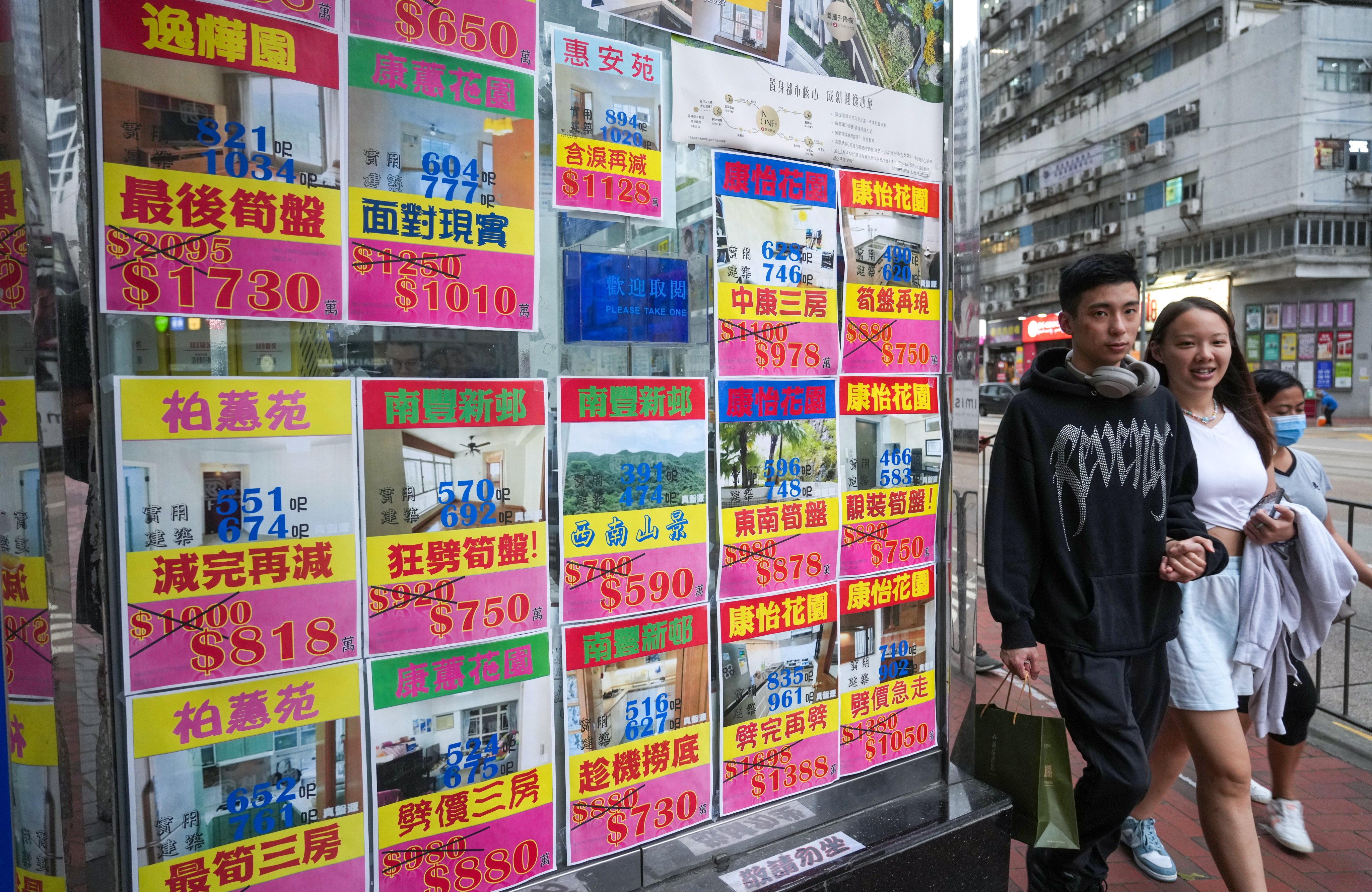 People walk past property advertisements in Quarry Bay on April 19. Even though home prices have fallen in recent years, they are still beyond the reach of many in Hong Kong. Photo: Sam Tsang