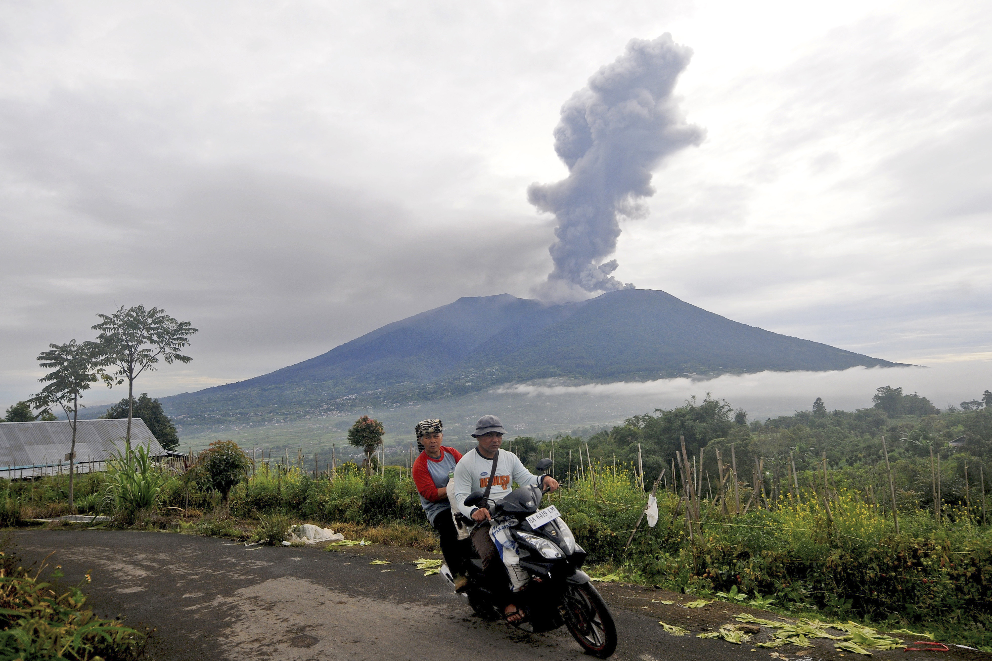 Motorists ride past as Mount Marapi spews volcanic materials during its eruption in Agam, West Sumatra, Indonesia on December 4, 2023. Photo: AP