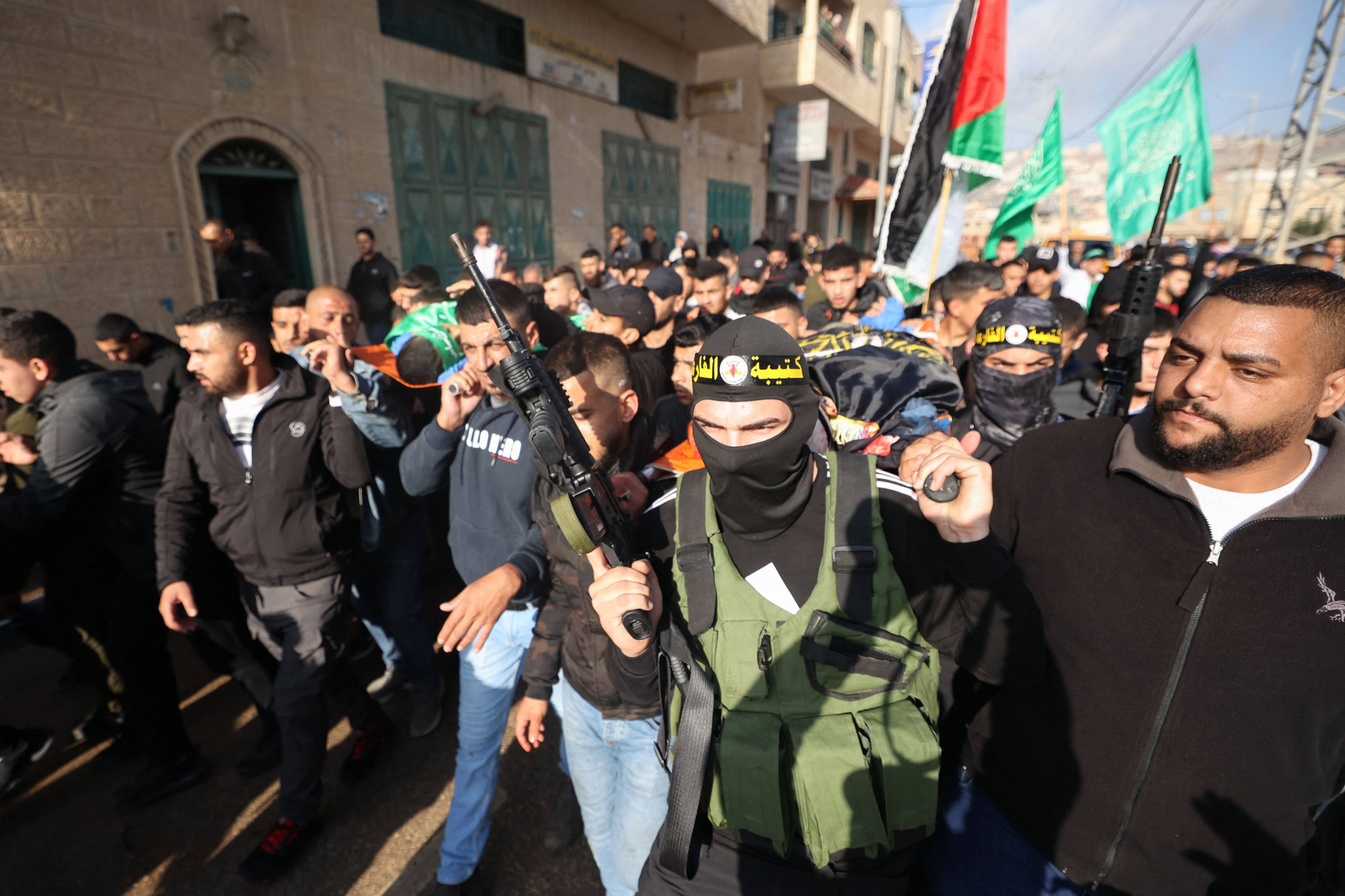Palestinian mourners and masked armed fighters at a funeral procession of two men who were fatally shot during a raid by Israeli troops in the occupied West Bank, on December 6 in the village of Tubas. Photo: AFP