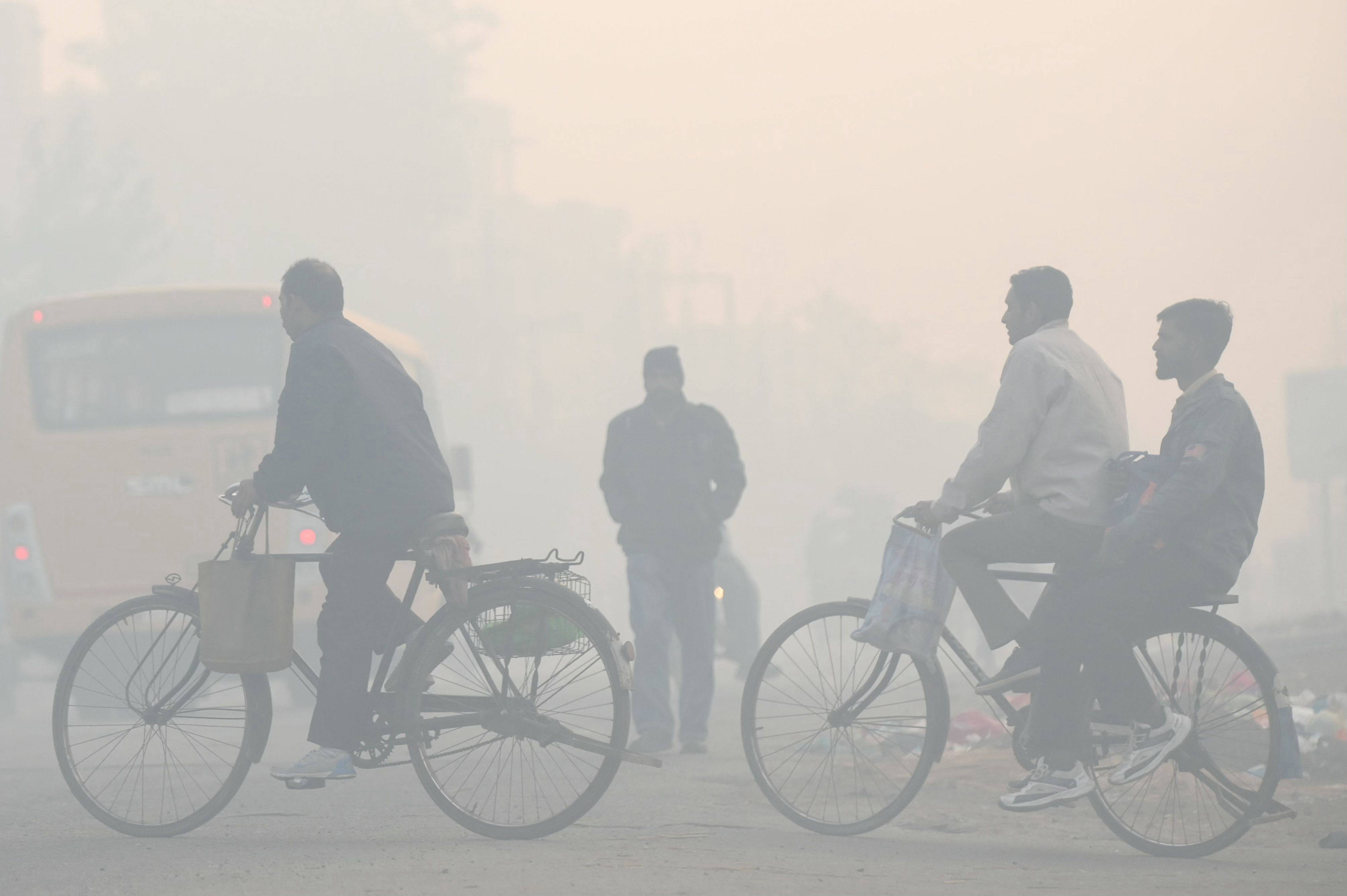 Men ride bicycles along a street, amid dense smog in the outskirts of Amritsar, India on Tuesday. Photo: AFP