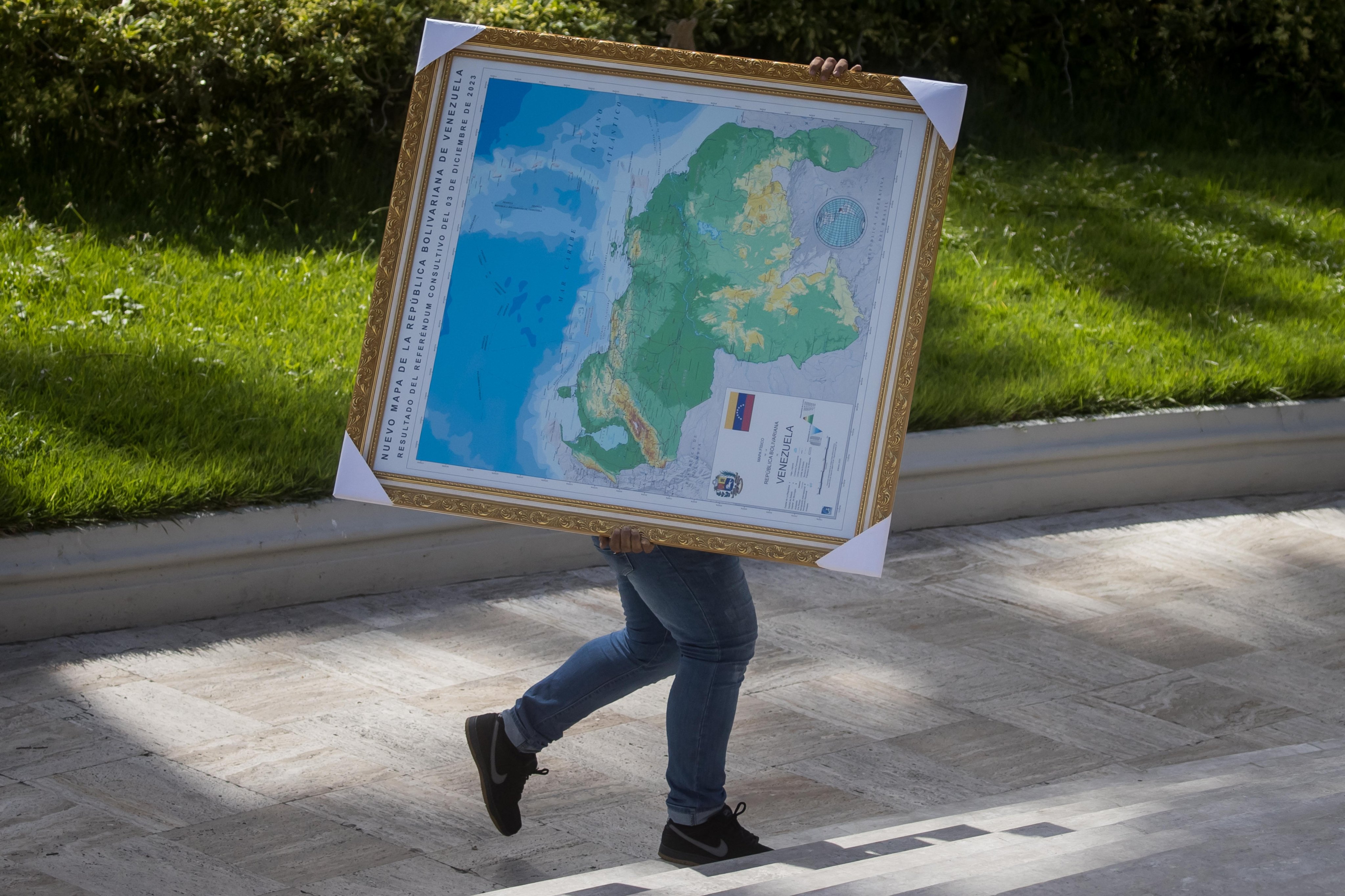 A man in Caracas carries a framed map of Venezuela, showing the disputed Essequibo region as part of Venezuela. Photo: EPA-EFE