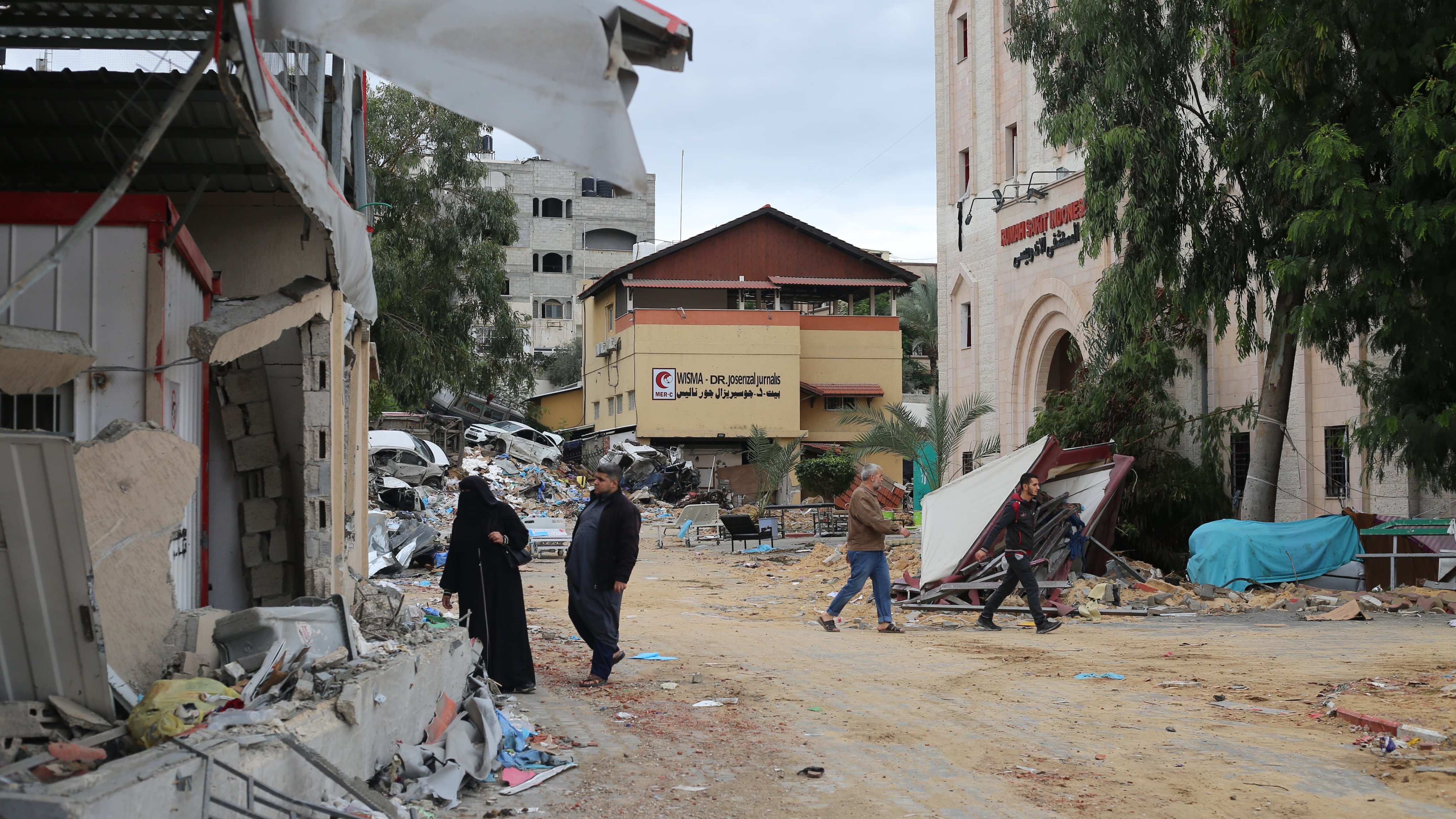 People walk amid rubble near the destroyed Indonesian hospital in Beit Lahia, north of the Gaza Strip, in Palestine on November 29. Healthcare facilities and workers have come under attack in recent conflicts despite international laws meant to ensure their safety. Photo: dpa
