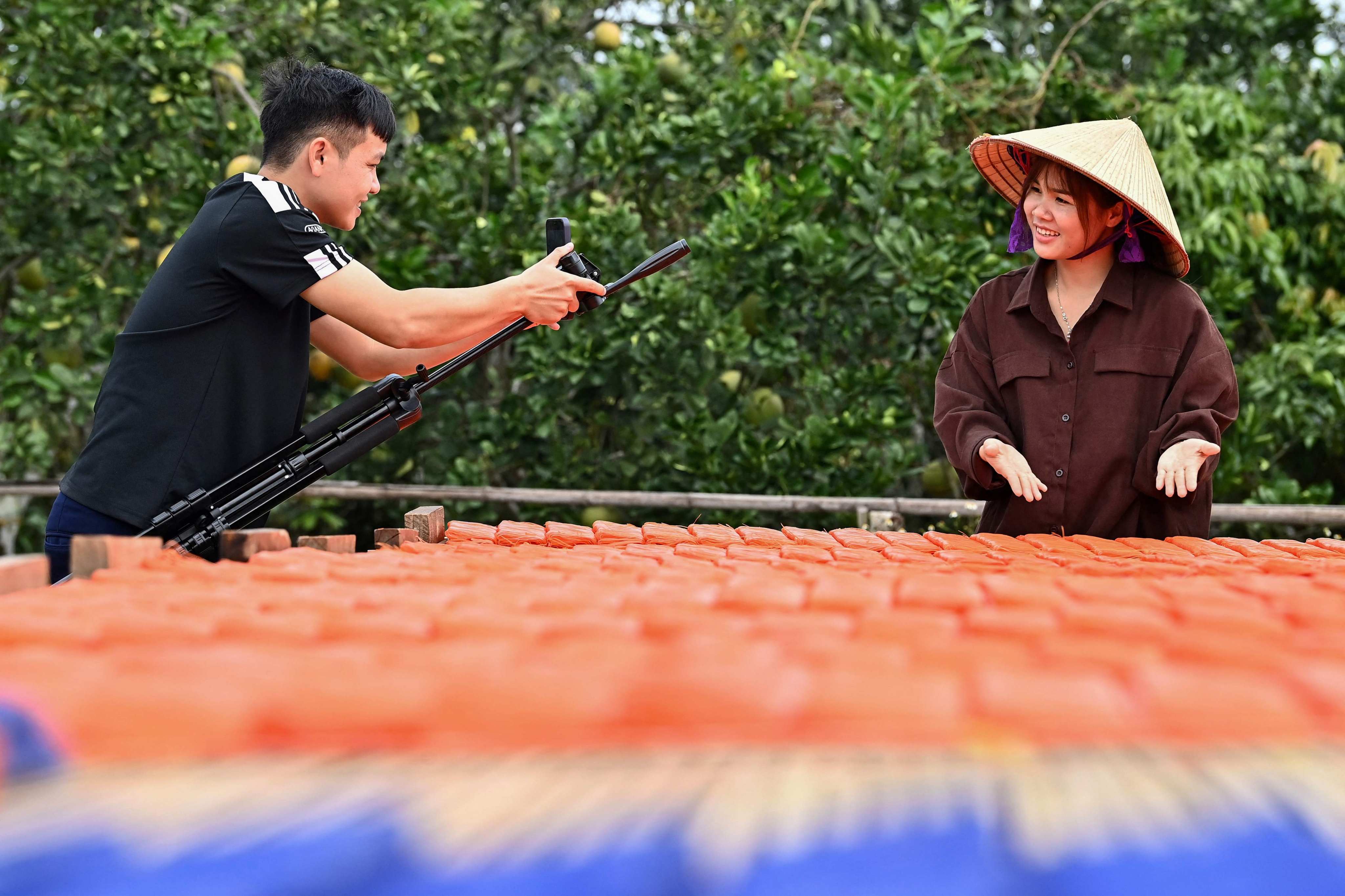 Vi Thi Anh’s husband shoots a video of his wife drying noodles at her workshop in Bac Giang province, Vietnam. Photo: AFP
