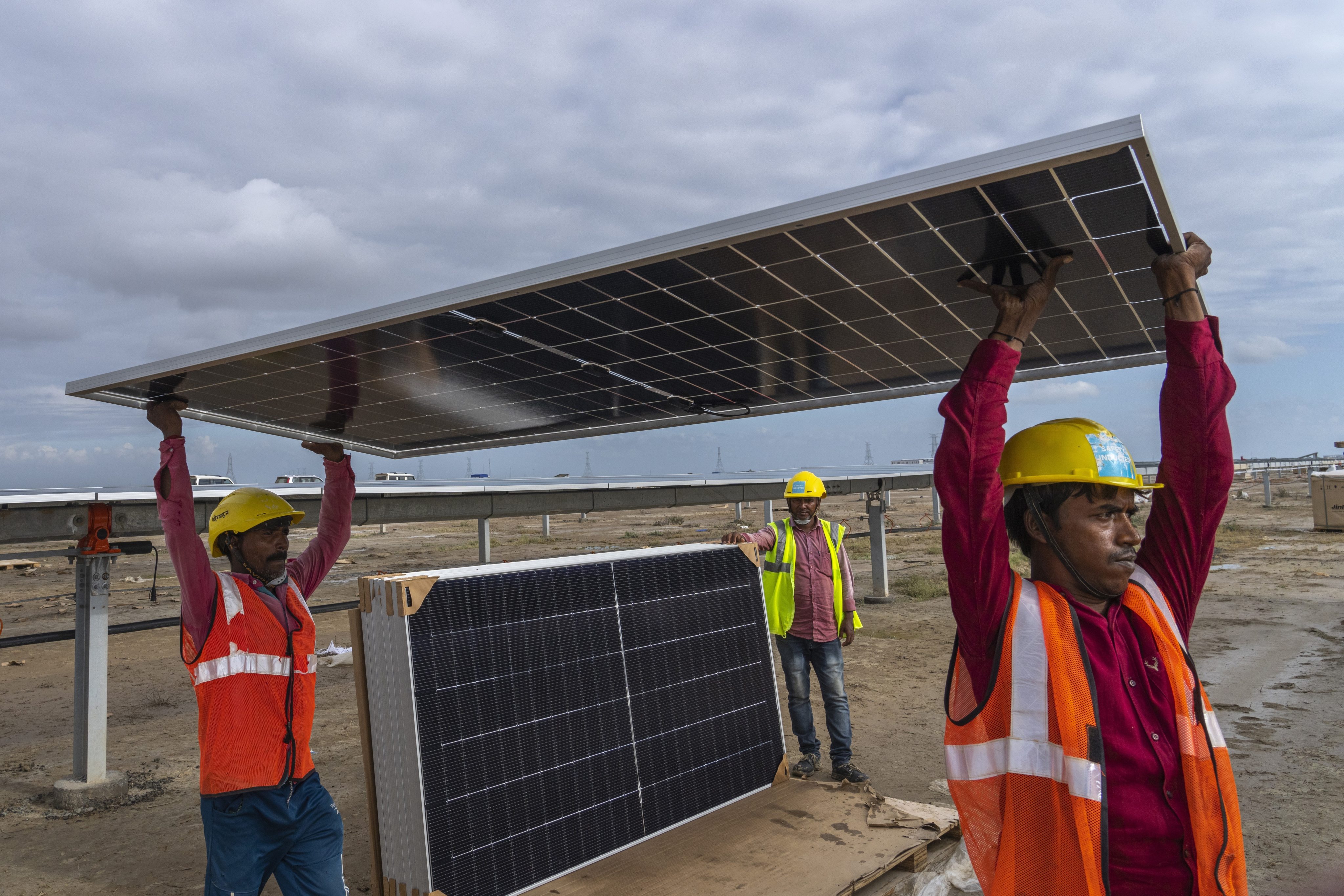 Workers carry a solar panel for installation at the Adani Green Energy Limited’s renewable energy park in the salt desert of Karim Shahi village, near Khavda in Gujarat, India, on September 21. Photo: AP