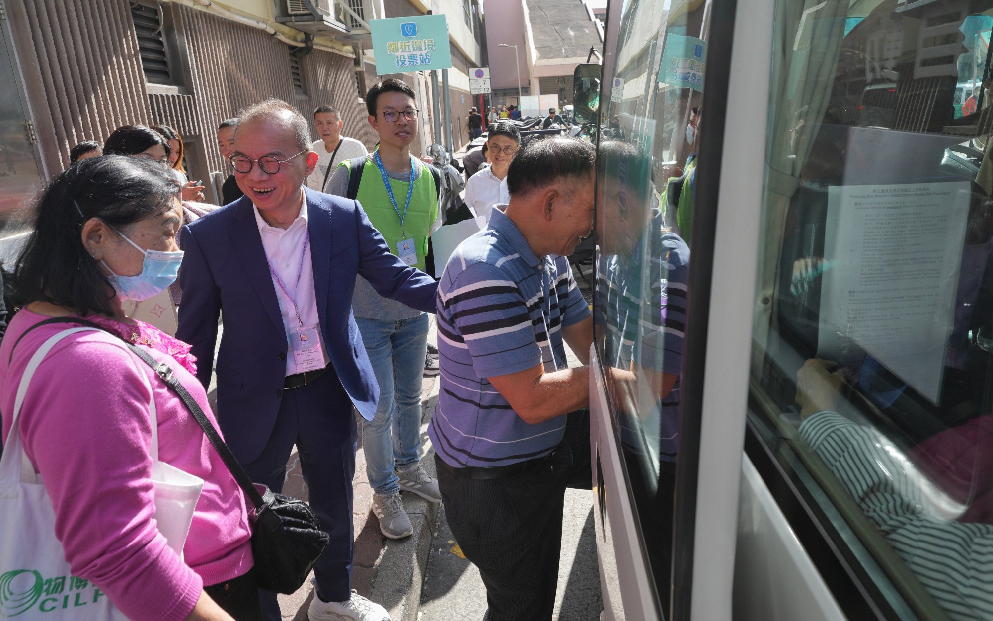 Secretary for Constitutional and Mainland Affairs Erick Tsang helps voters take a shuttle bus to two border polling stations outside the Sheung Shui MTR station. Photo: Elson LI