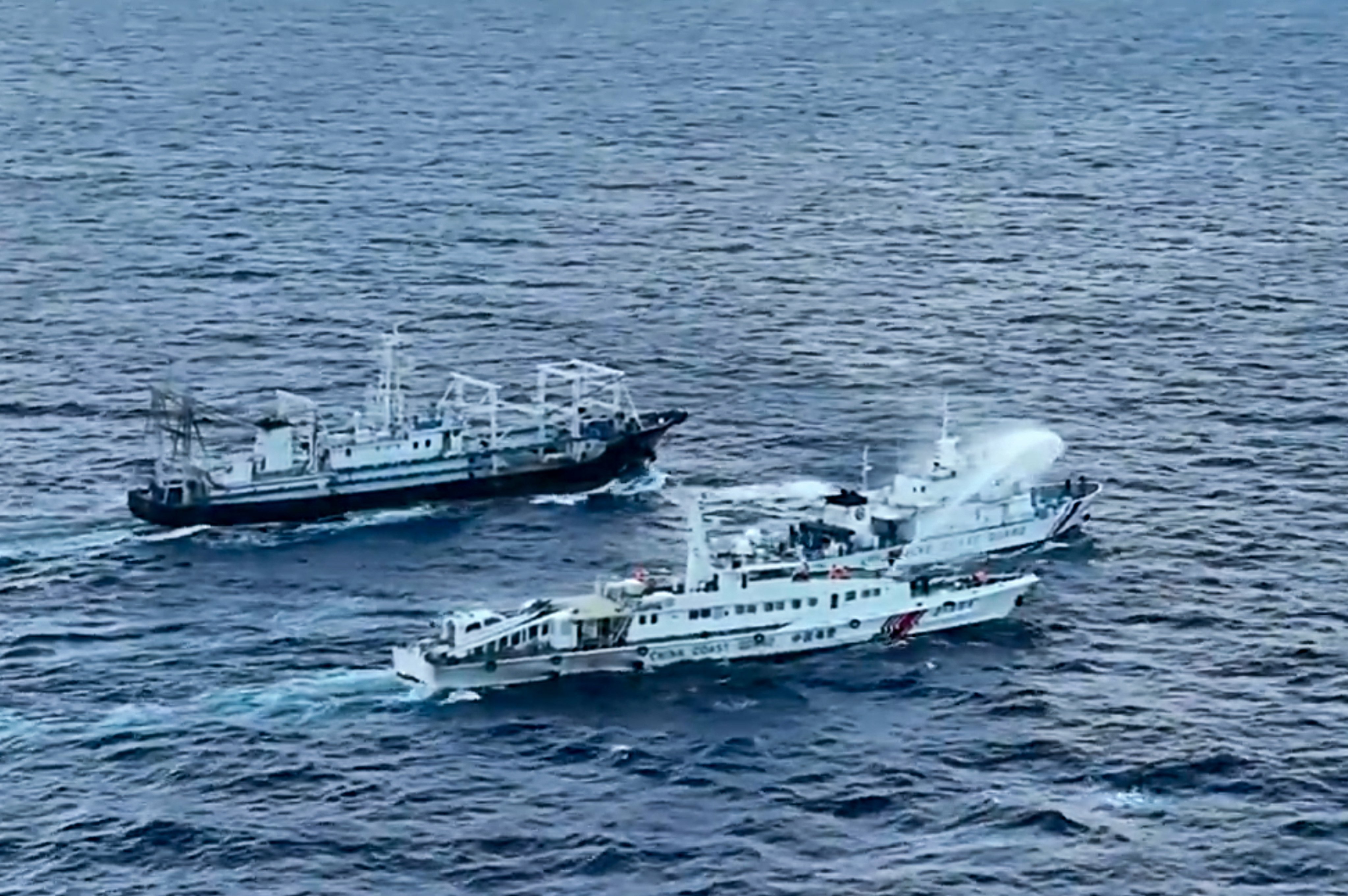 An image from video provided by the Philippine Coast Guard shows a Chinese Coast Guard ship, bottom, using a water cannon on a Philippine ship, BRP Cabra, centre, as it approaches Second Thomas Shoal on Sunday. Photo: Philippine Coast Guard